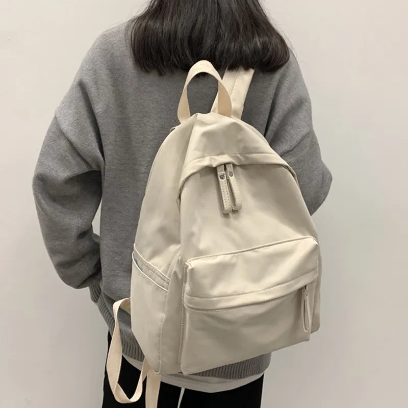Ivory cotton zip backpack worn with front zip pocket and adjustable straps