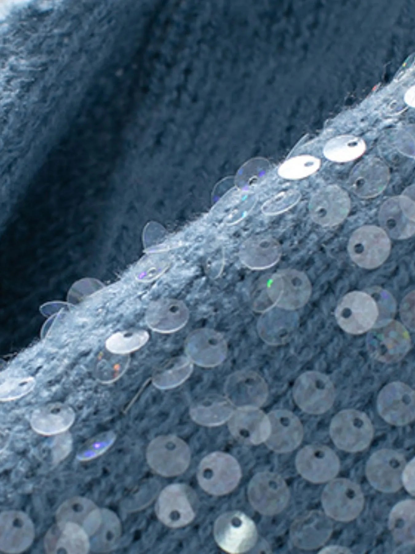 Blue knit fabric with scattered round sequin discs on the sleeve