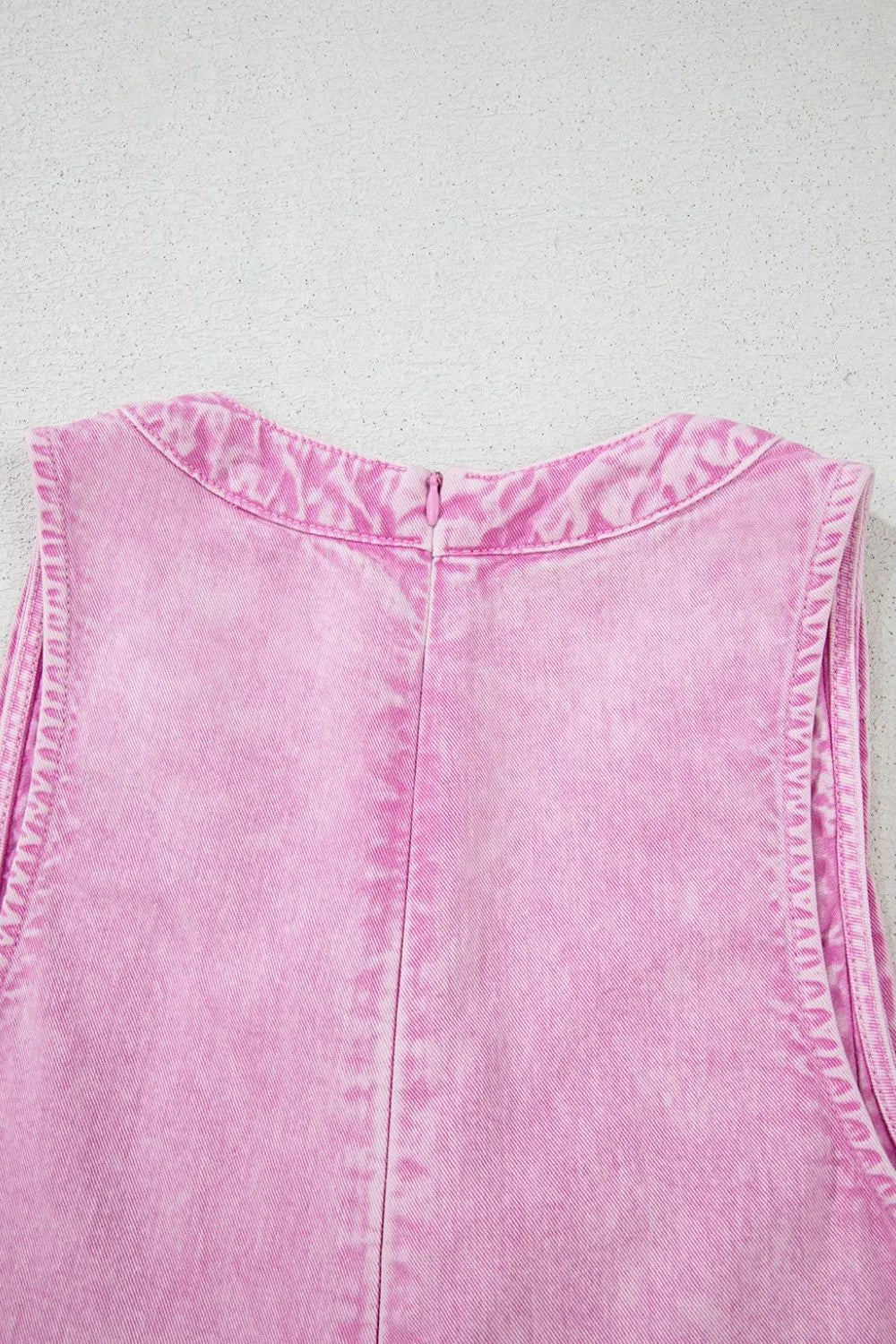 Pink mineral-wash denim romper close-up of back yoke and center seam
