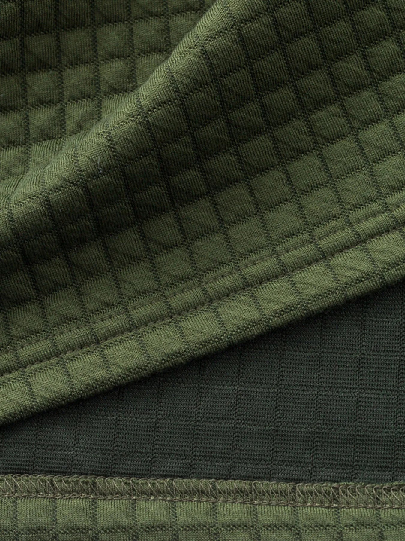 Dark green textured fabric hem with seam line and ribbed trim detail