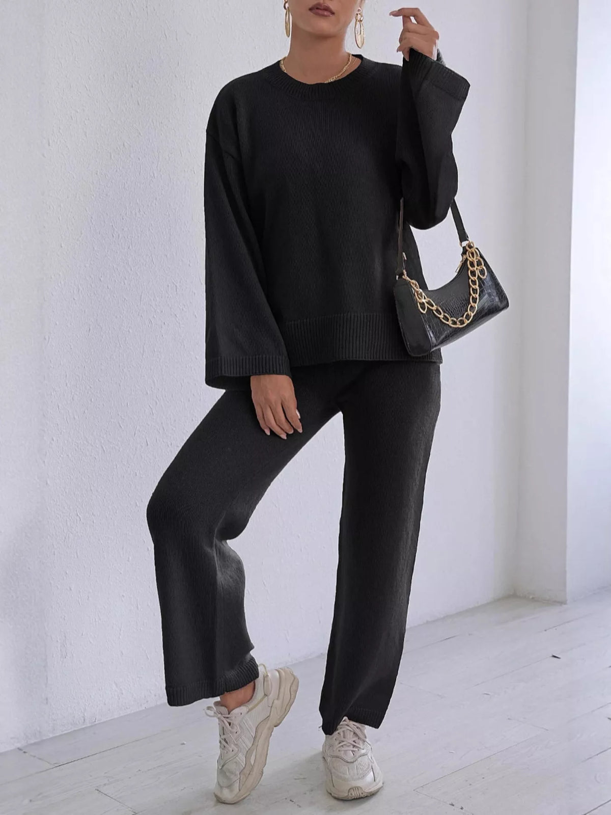 Black knit sweater and pants set with dropped shoulders, crew neck, and ribbed hem cuffs.