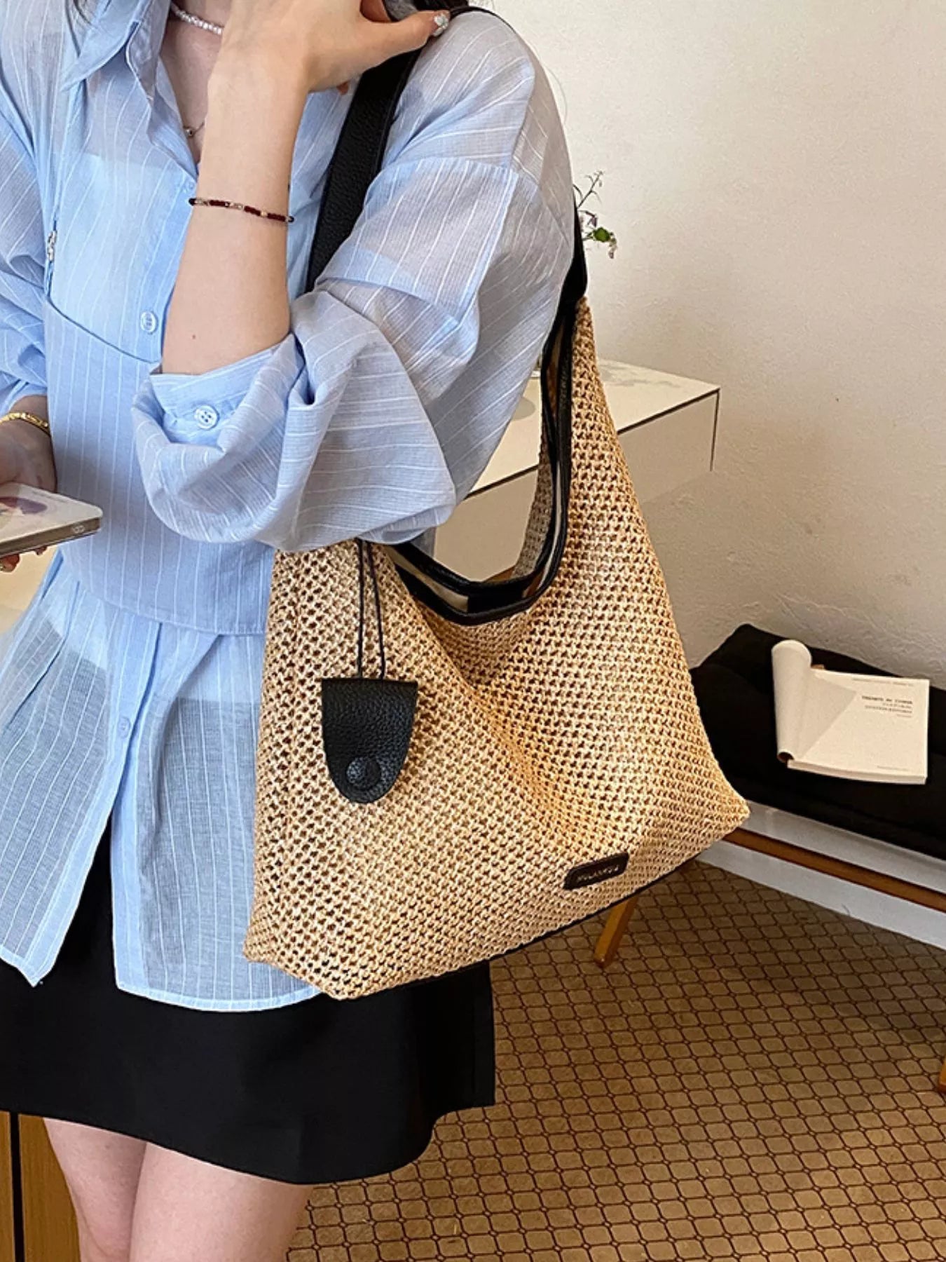 Camel woven straw shoulder bag with black handle straps and front pocket detail
