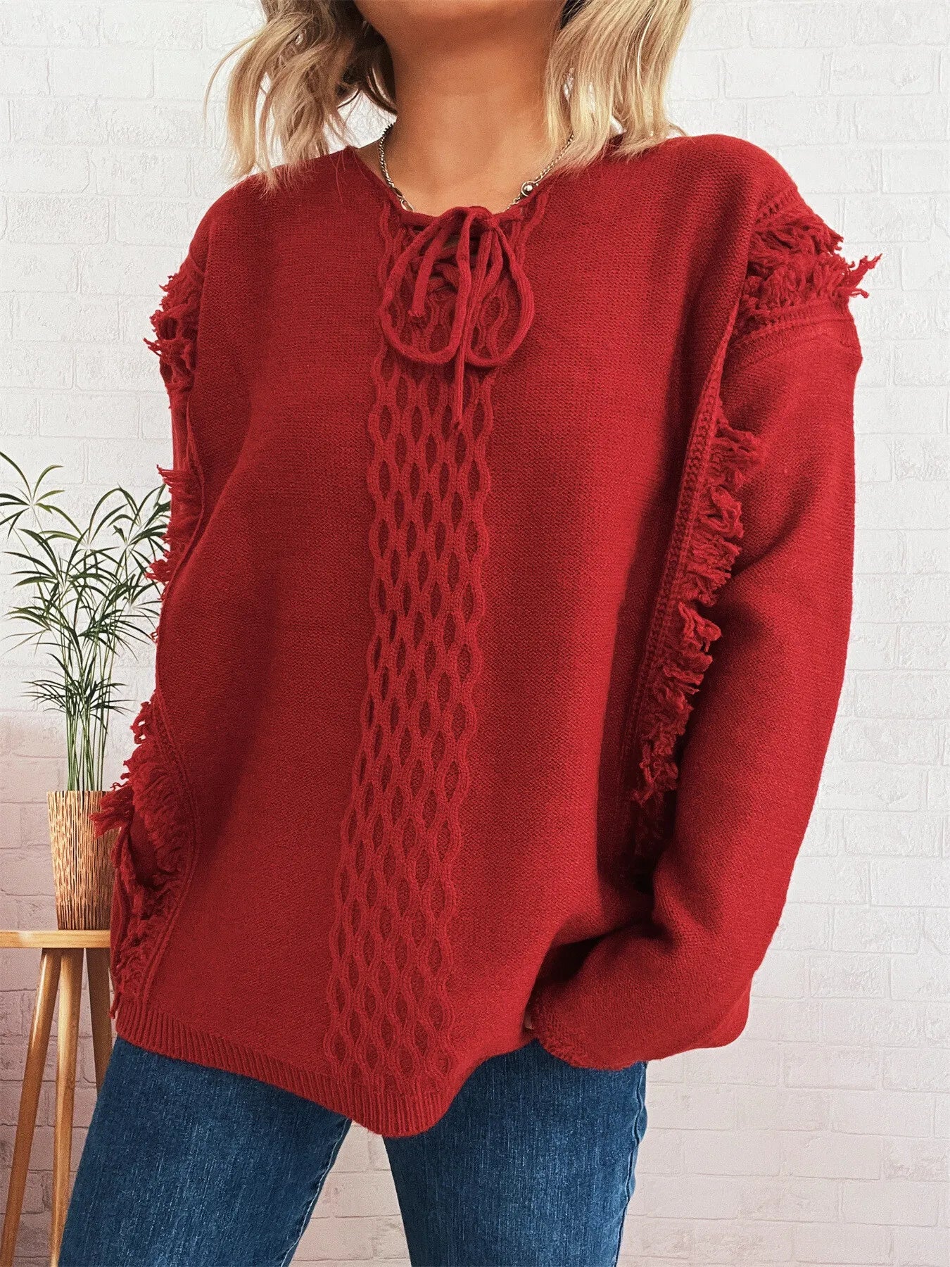 Burgundy lace-up sweater with cable knit texture and raw fringe sleeve detail