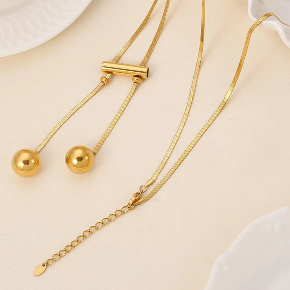 Gold-tone hollow bead necklace with long cords and small chain extender