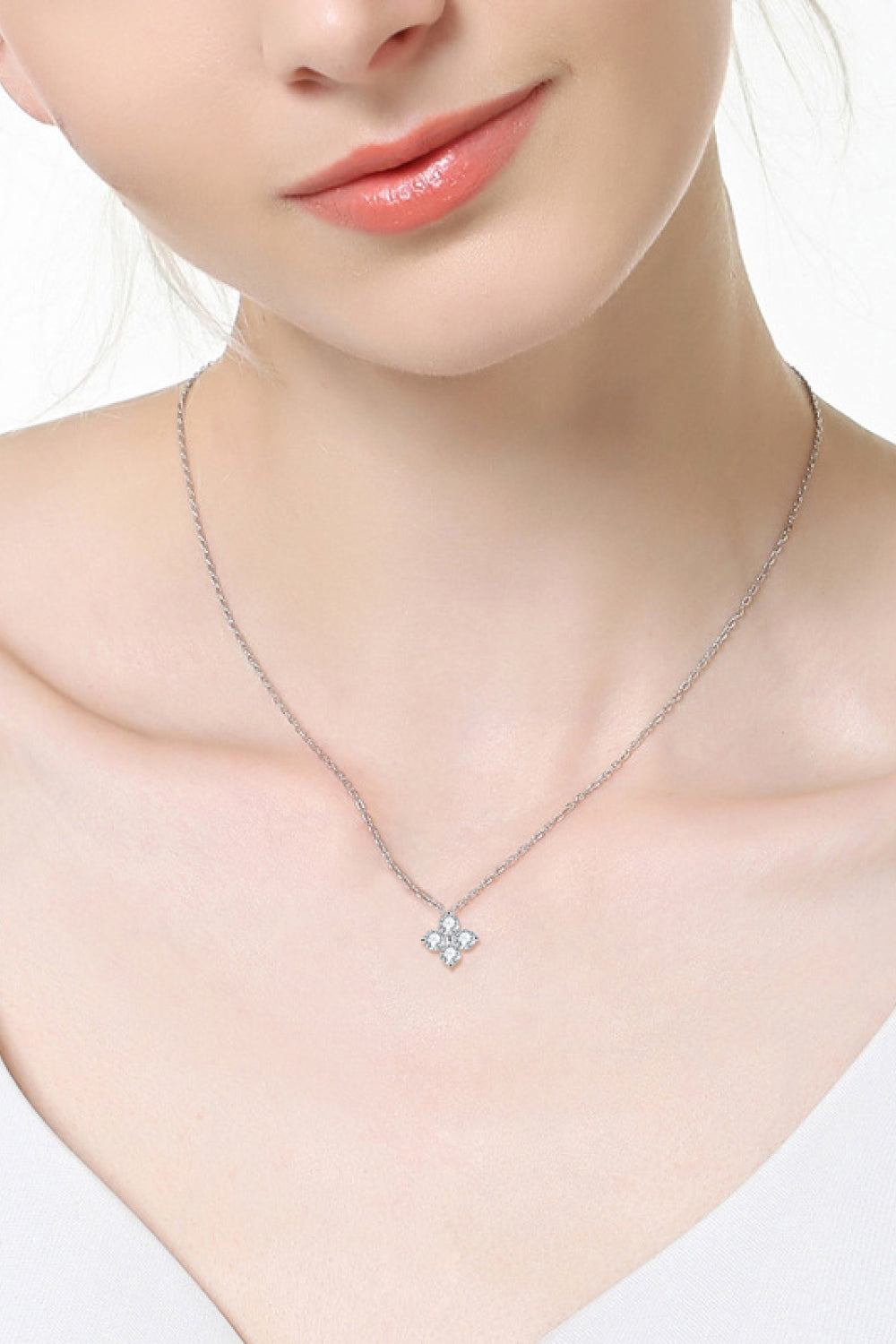 Silver-tone clover pendant necklace with a small sparkling center stone on a thin chain
