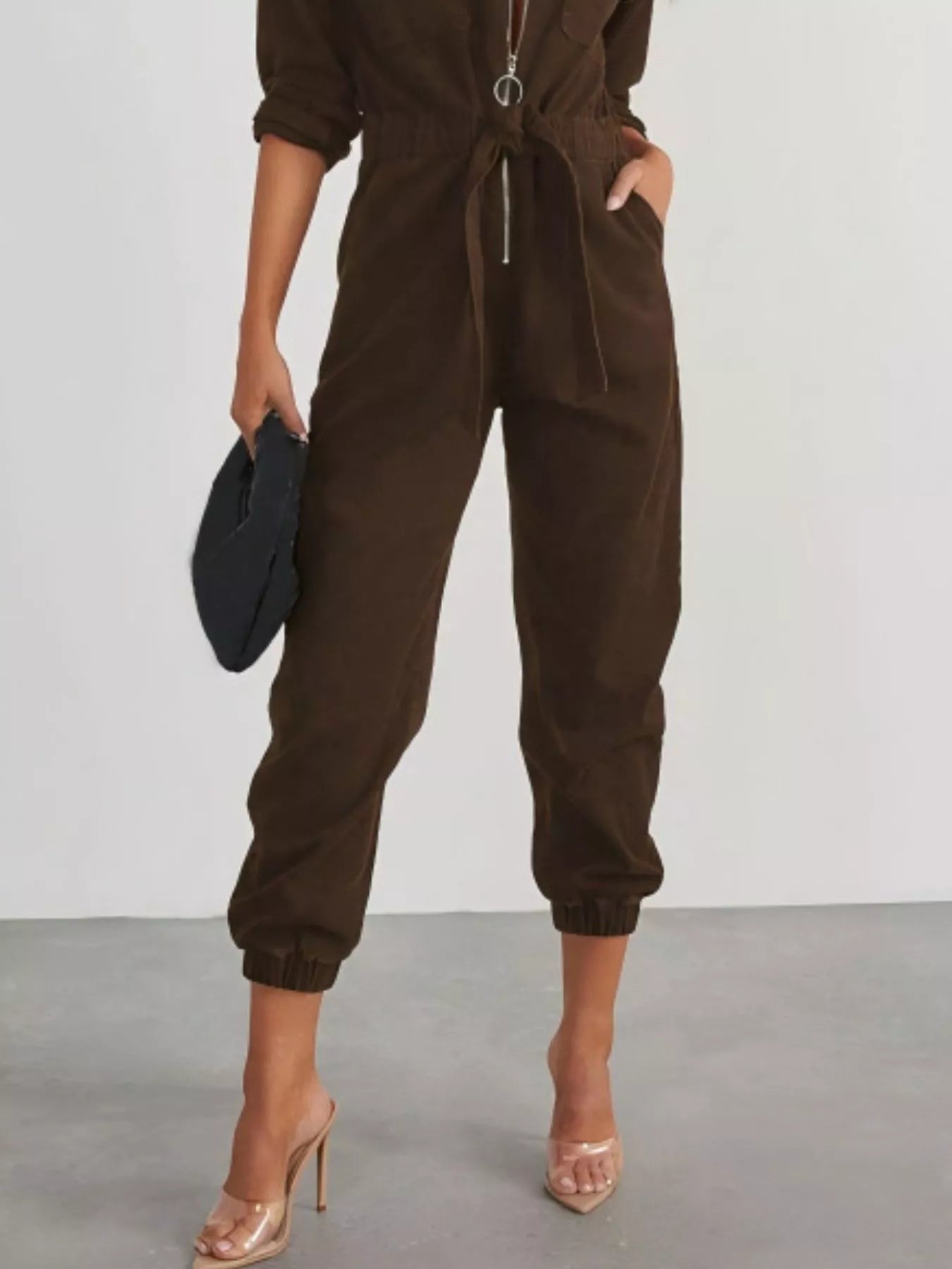 Dark brown long-sleeve zip-front jumpsuit with tie waist and cuffed tapered legs
