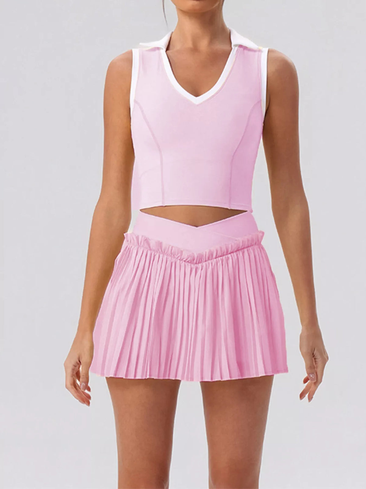 Two-piece sleeveless top and pleated skirt set in pastel pink with V-neck white trim