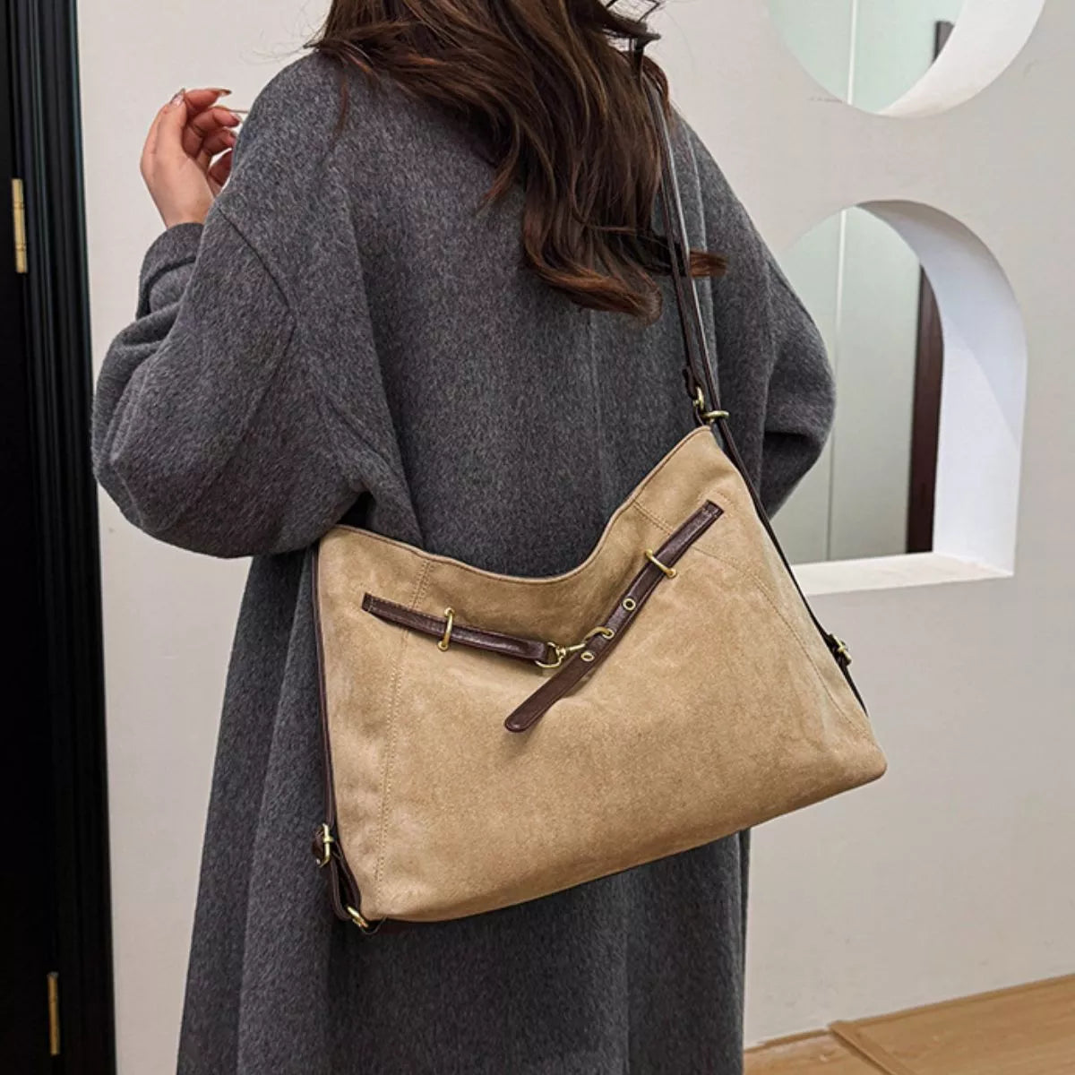 Tan suede shoulder bag with decorative buckle, side view, gold-tone hardware details