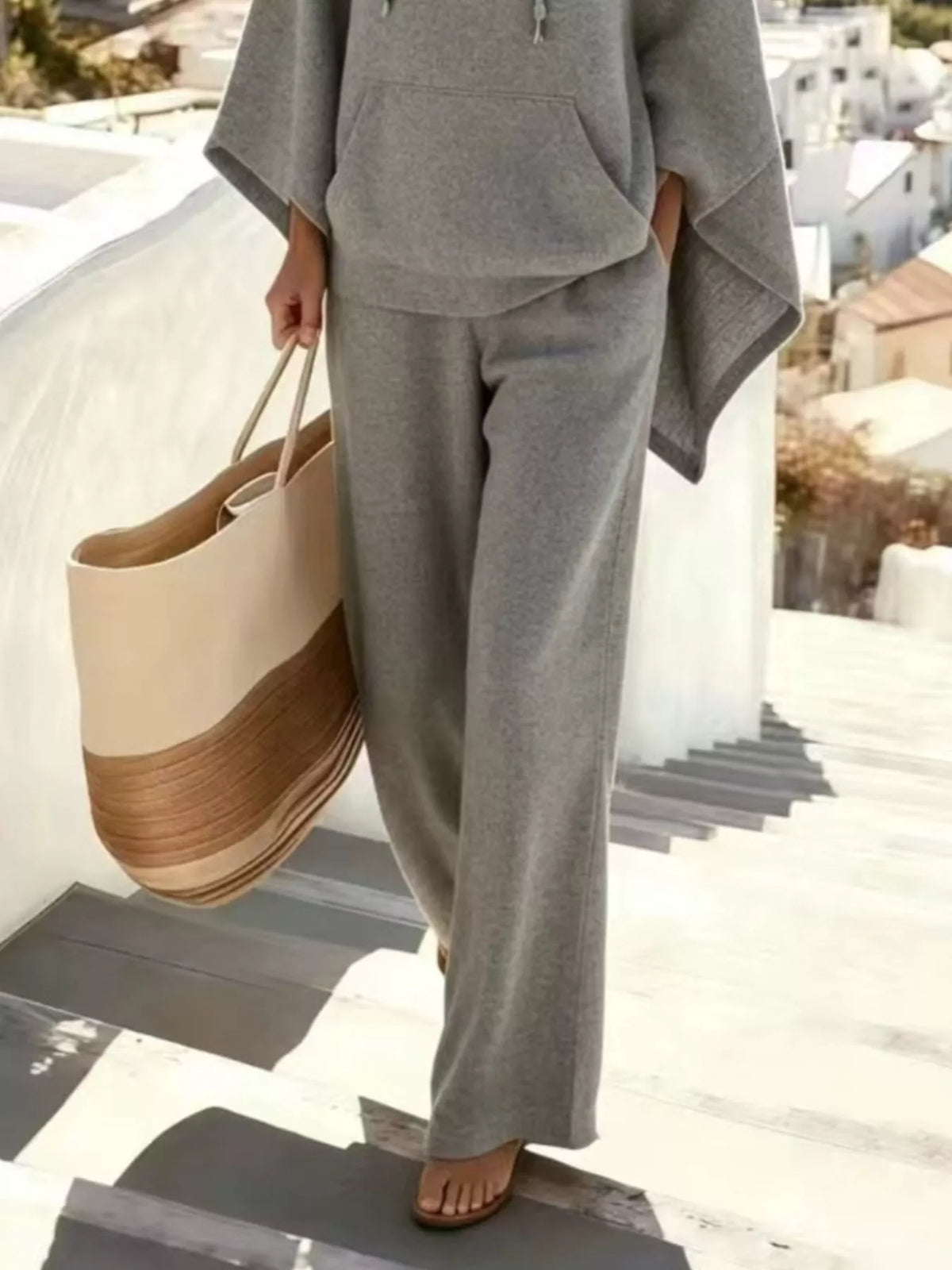 Gray wide-leg pants with hooded poncho overlay and drawstring details on hood