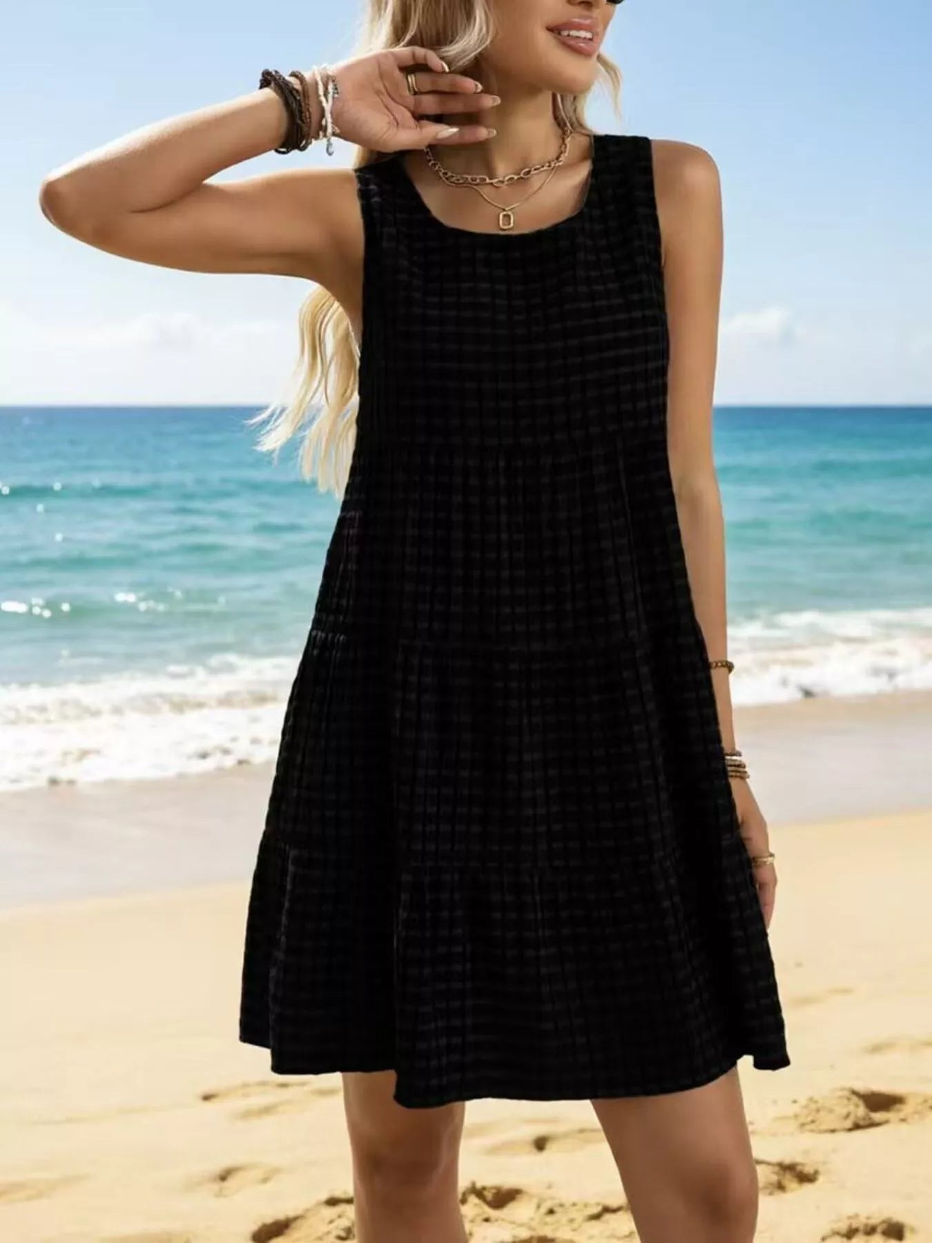 Black textured sleeveless tiered mini dress with round neckline and flared tiers