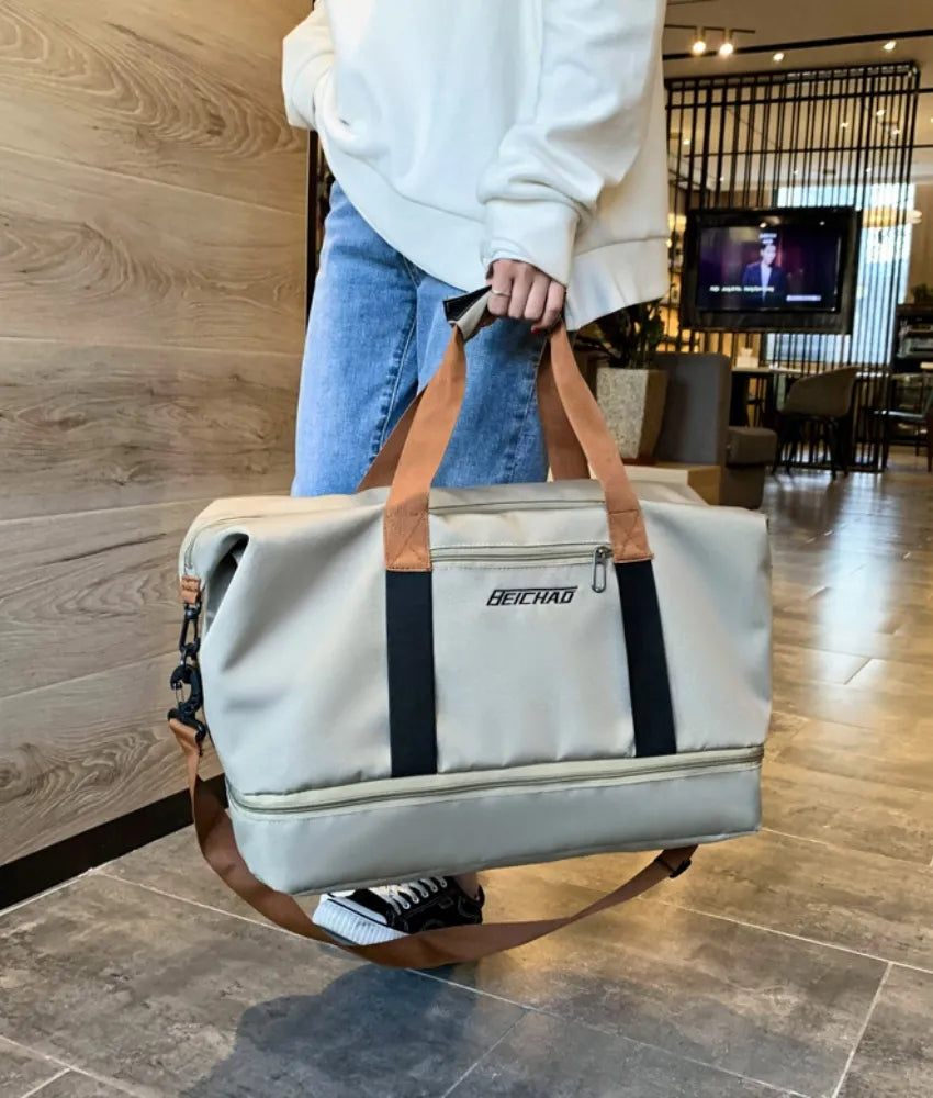 Oversize travel duffle bag in light gray with brown carry handles, black stripe, zip