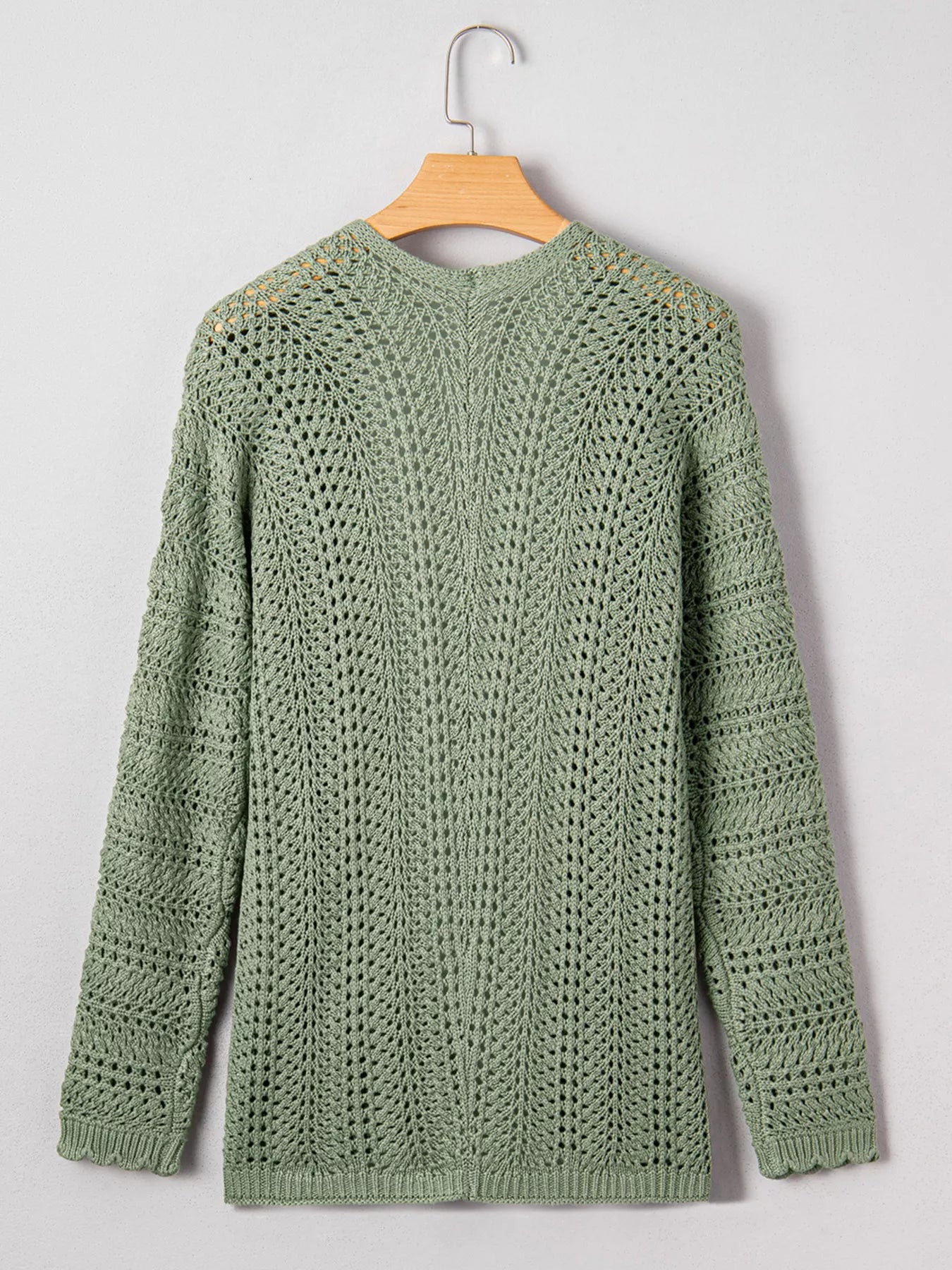 Sage eyelet knit cardigan with long sleeves and textured openwork knit, back hem.