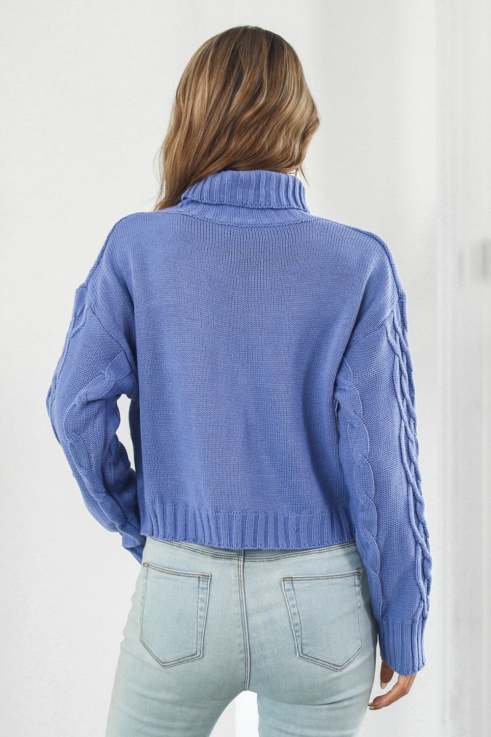 Blue cable-knit turtleneck sweater, back view with dropped shoulders