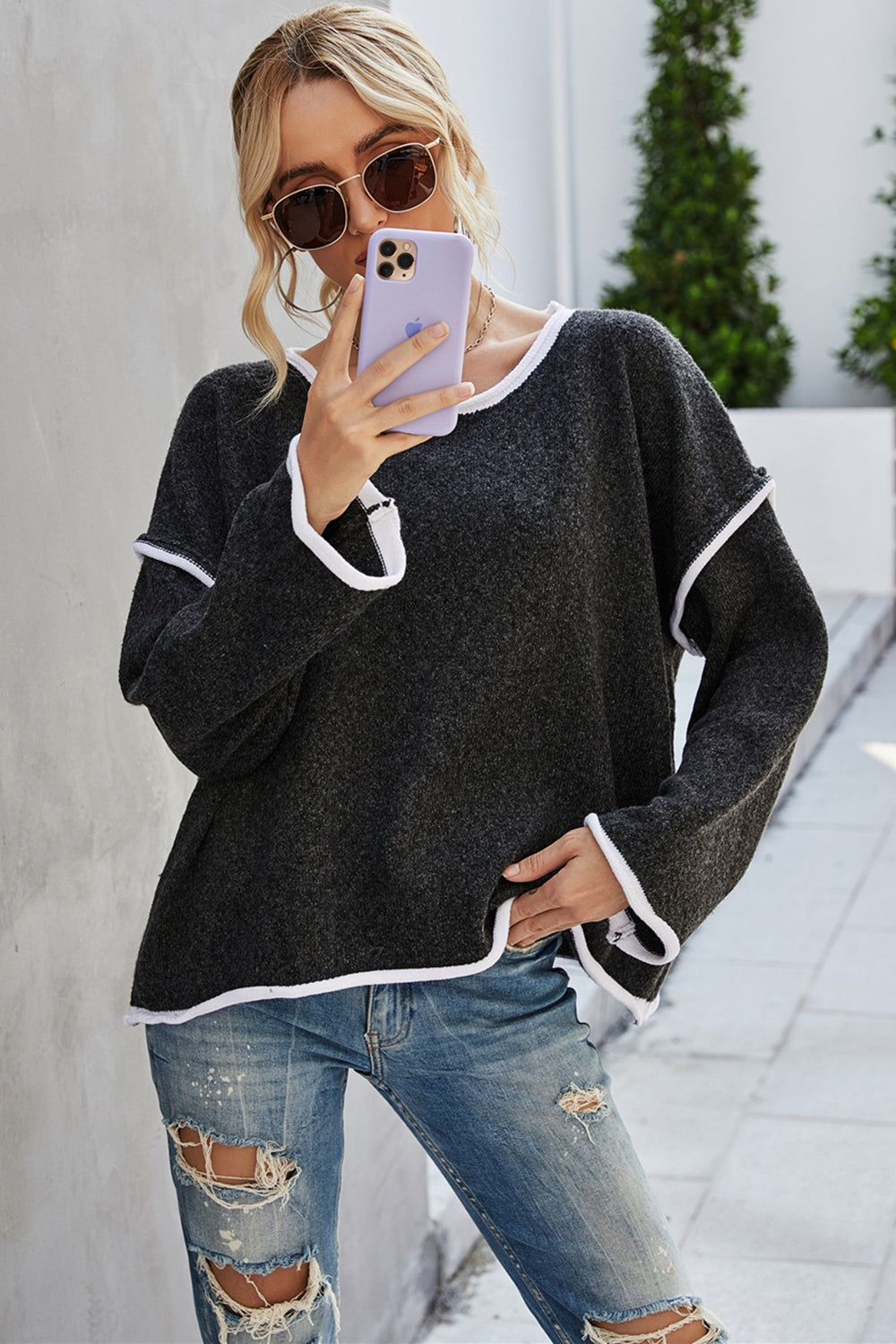 Black dropped-shoulder sweater with round neck and white contrast trim, front view