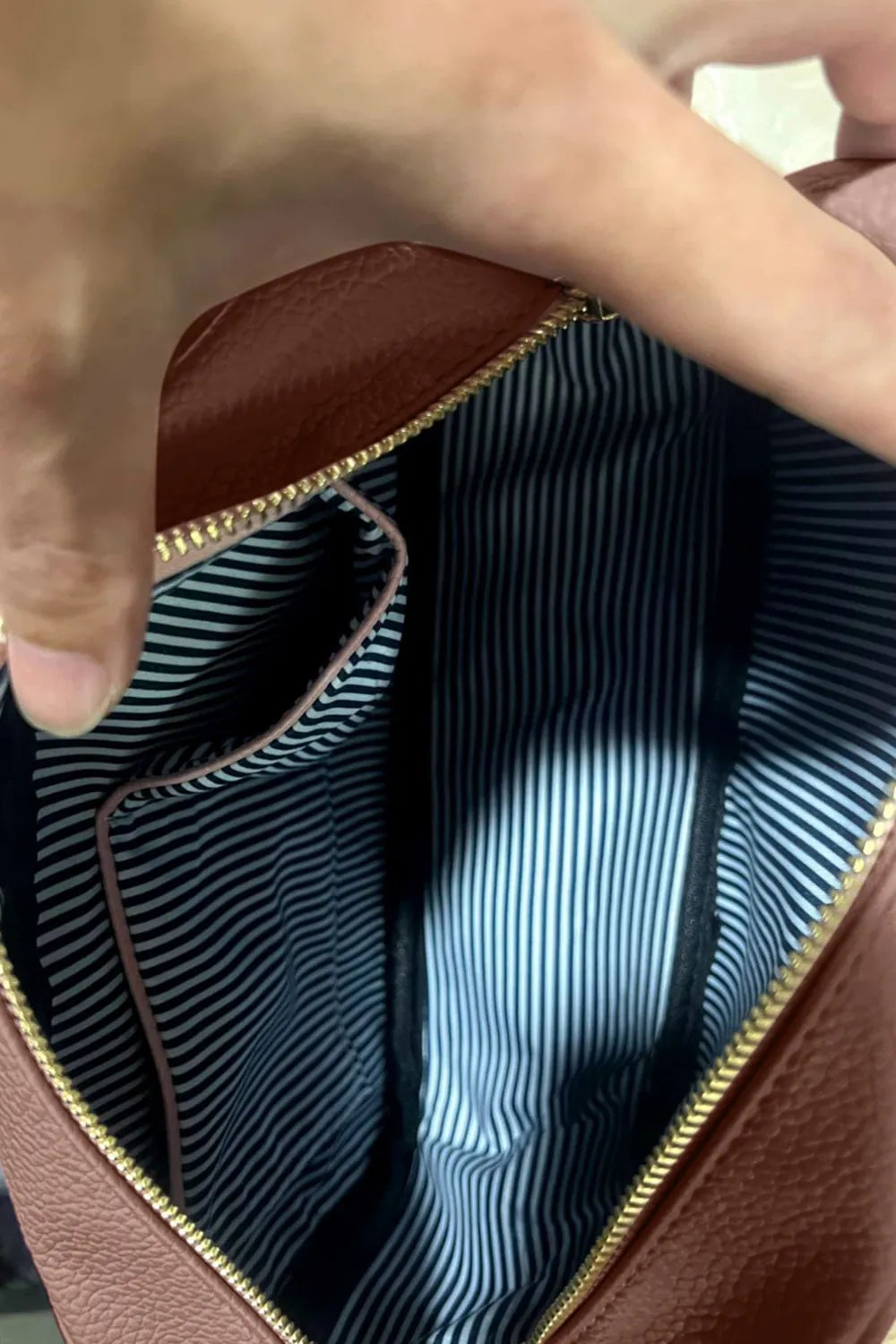 PU leather tassel crossbody bag interior view, brown exterior with striped lining and zipper