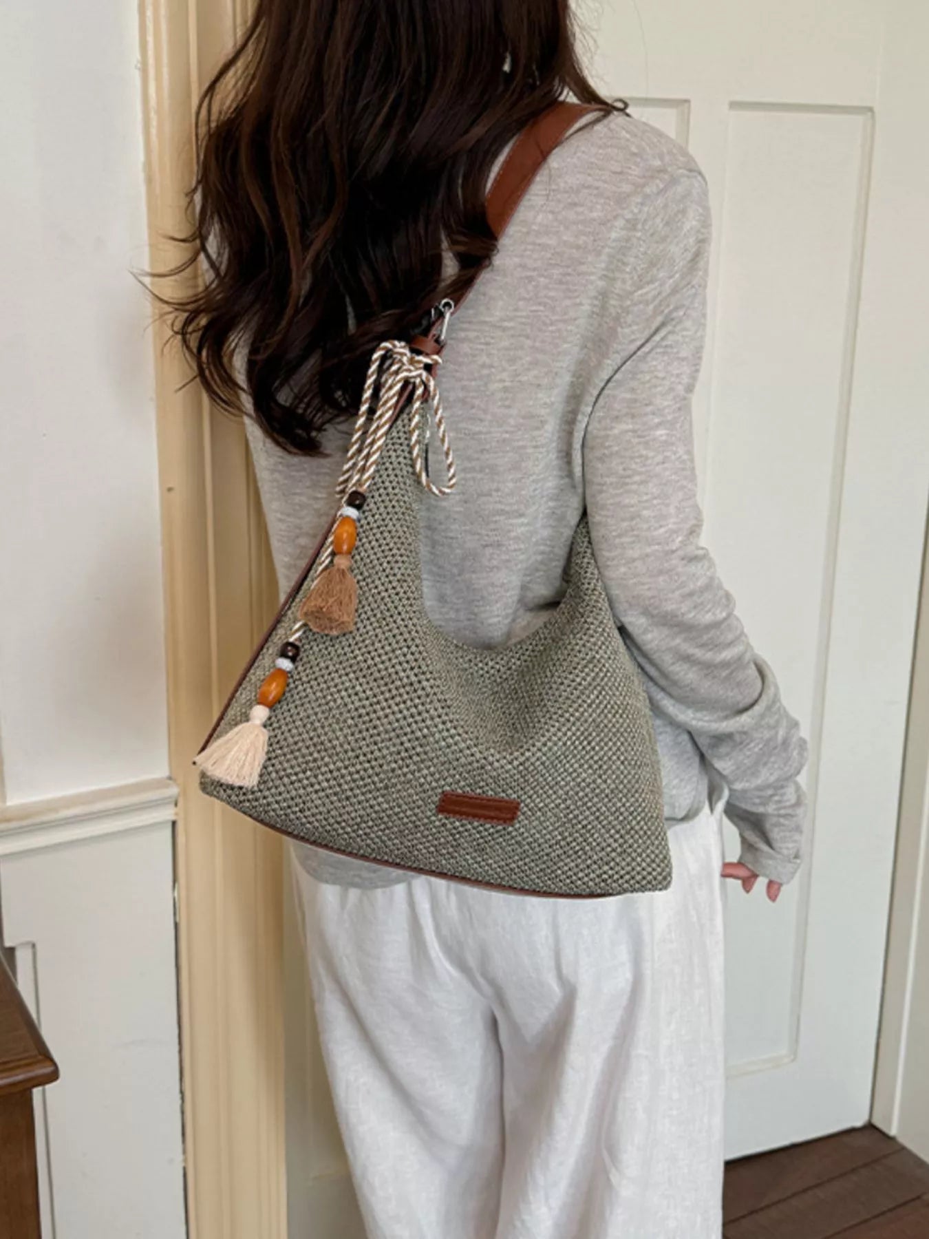 Medium woven shoulder bag from back view, textured gray woven fabric with tassel detail