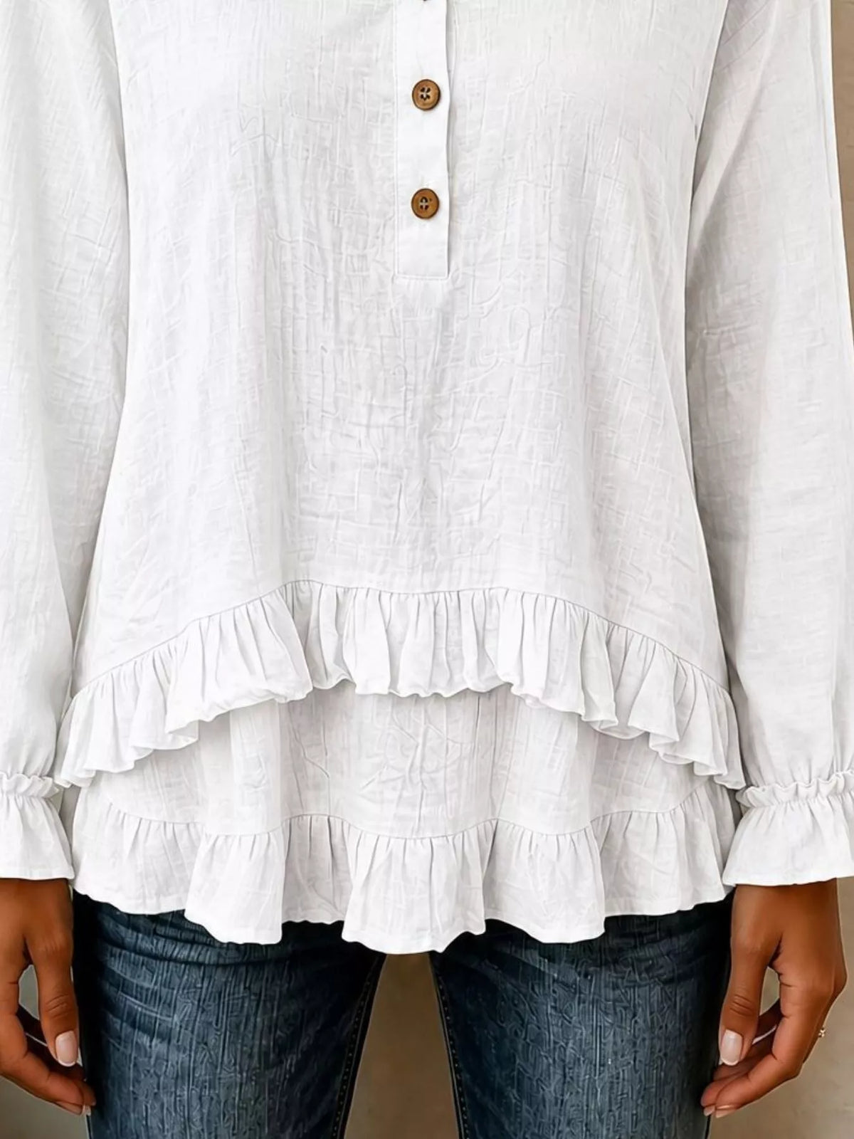 White long-sleeve blouse with layered ruffled hem and button placket