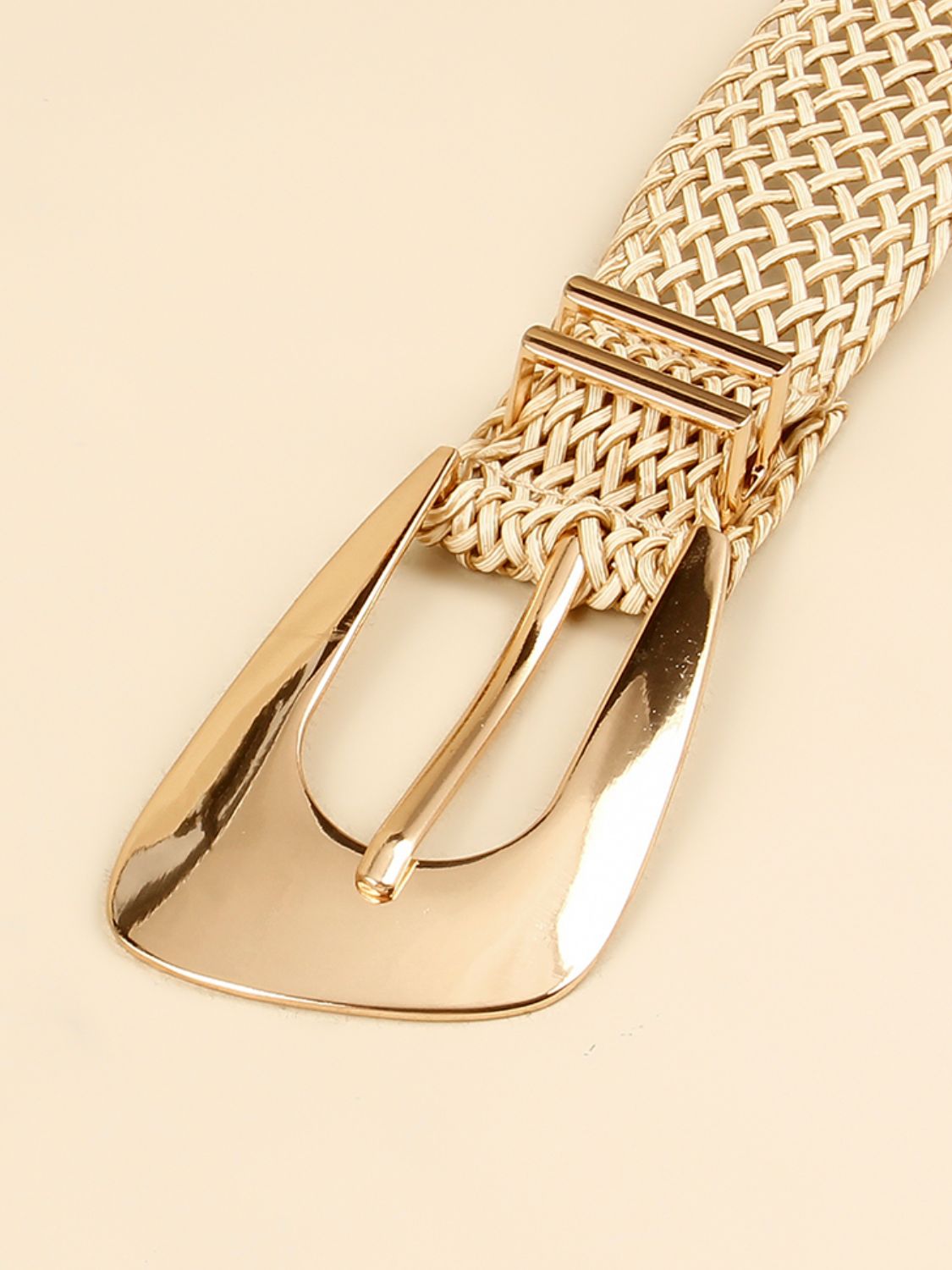 Close-up of gold-tone irregular buckle and braided woven belt strap