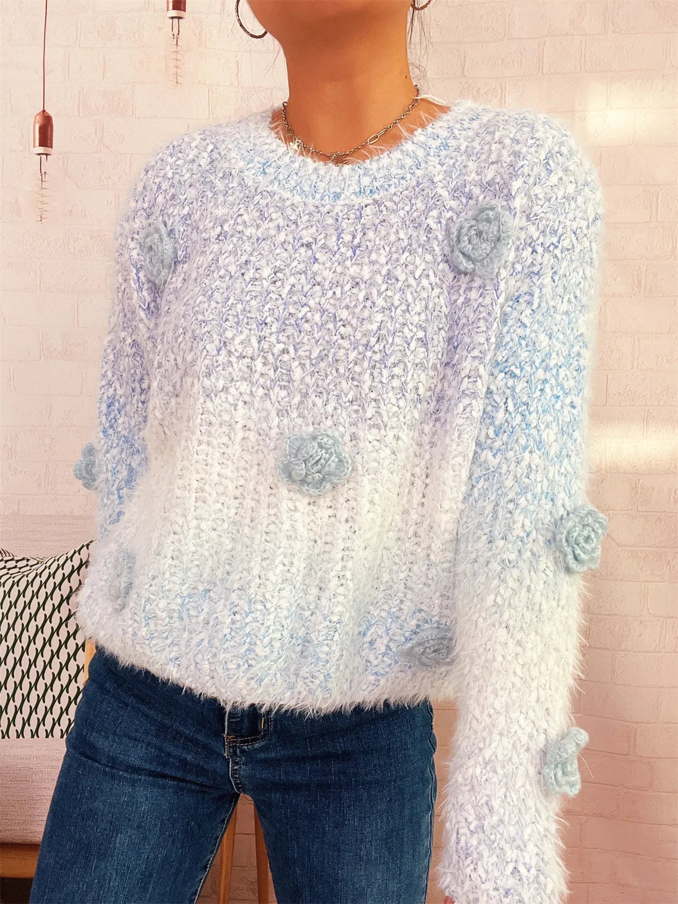 Light blue fuzzy knit sweater with round neck and flower appliques on sleeves.