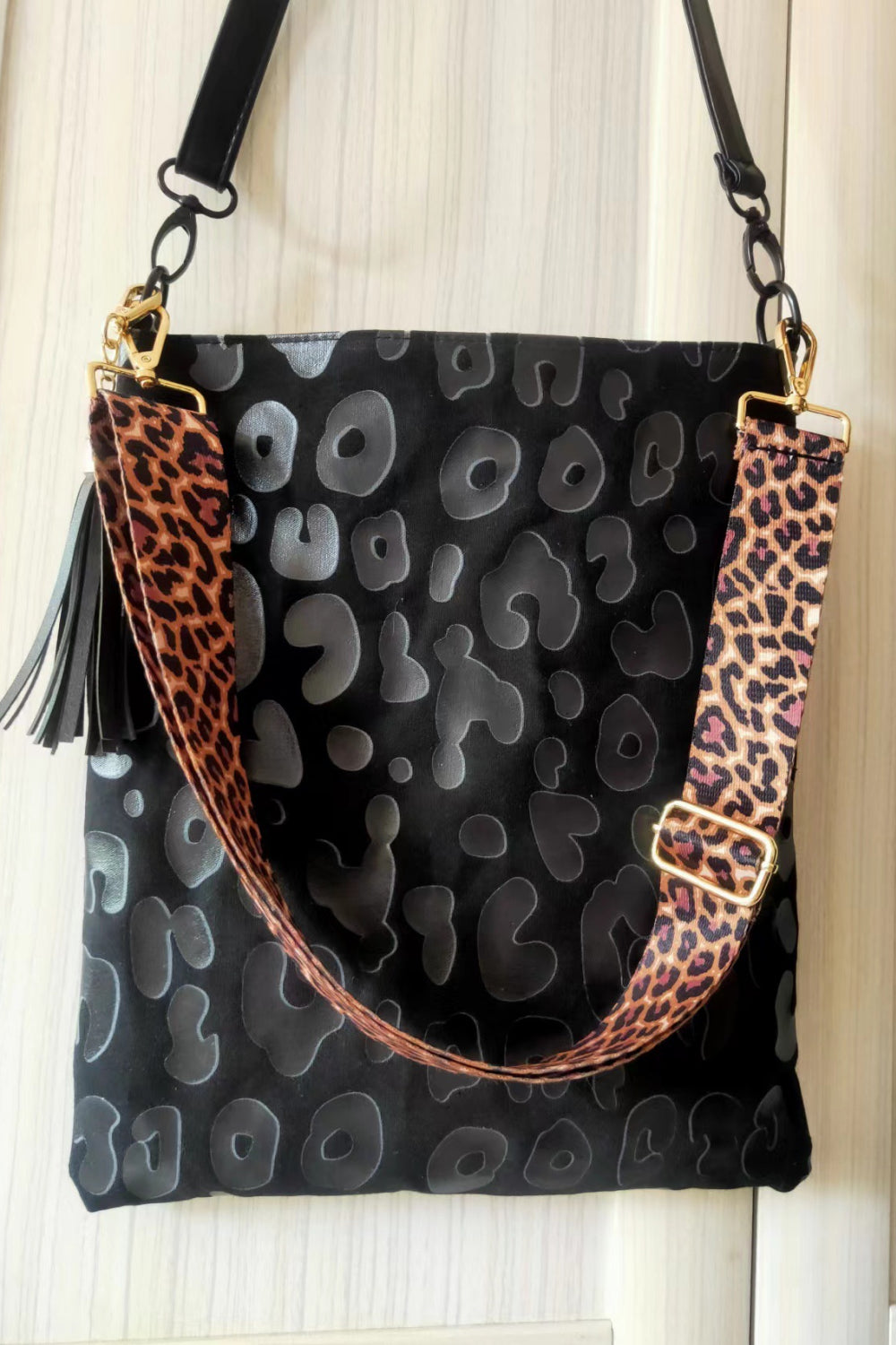 Black PU leather shoulder bag with embossed shapes, leopard trim, tassel and chain strap