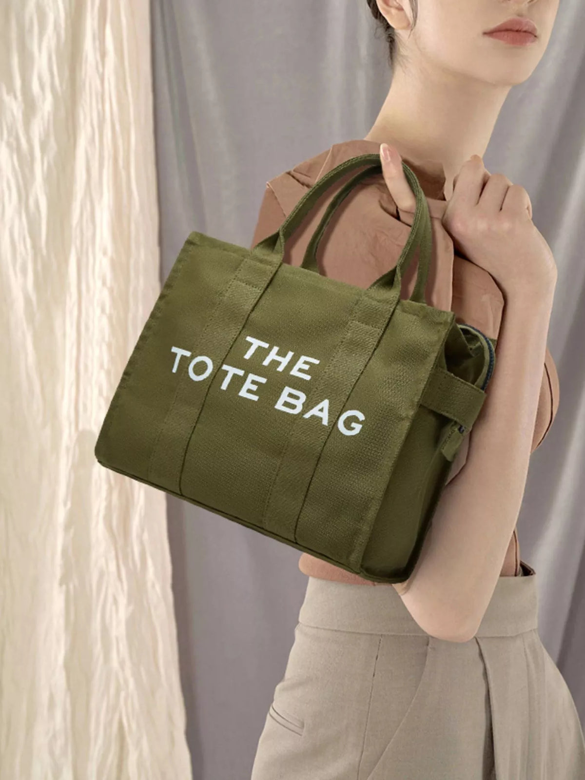 Army green canvas tote bag with “THE TOTE BAG” graphic and dual handles