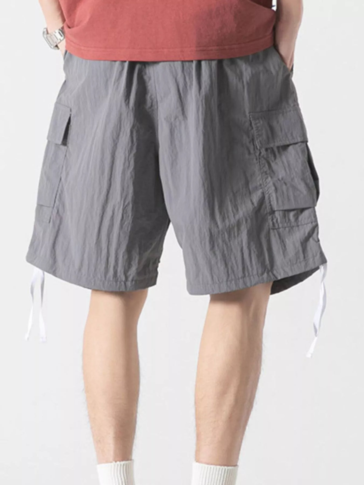 Gray cargo shorts with flap cargo pockets and hanging drawstrings at hem