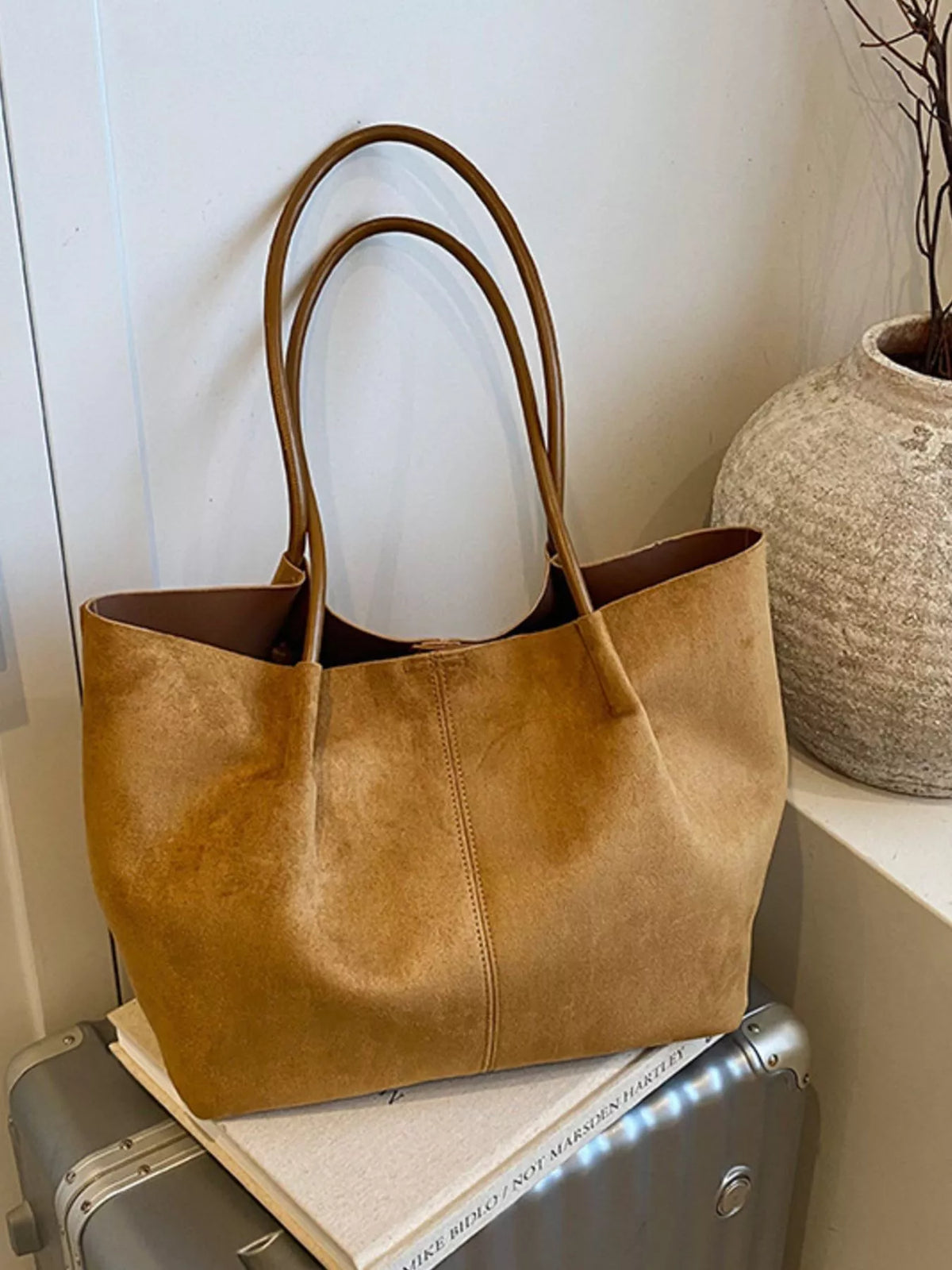 Tan suede tote bag with long handles and stitched front panel; minimal hardware.