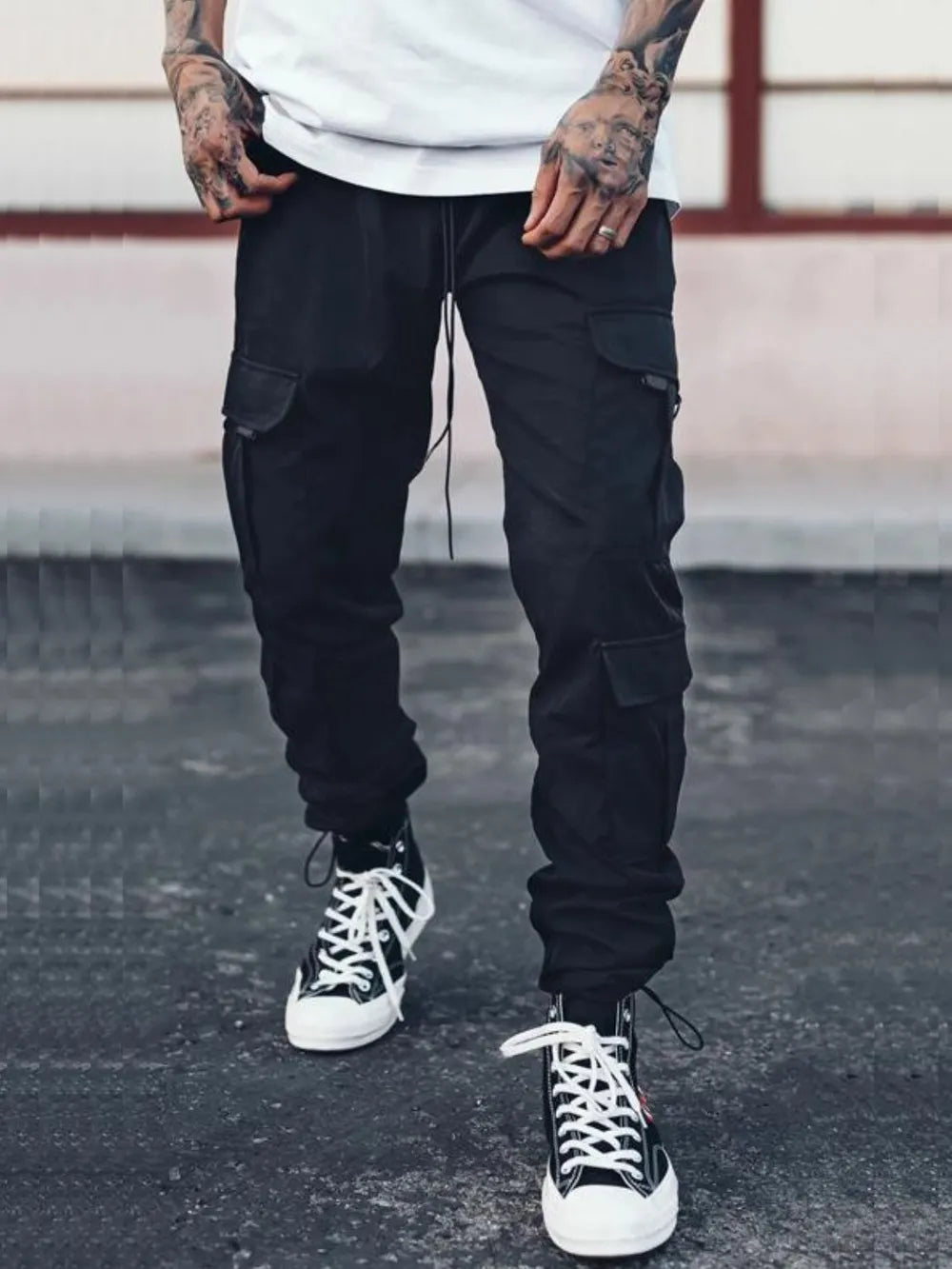 Men's black cargo pants with drawstring waist, side pockets, and jogger-style cuffs