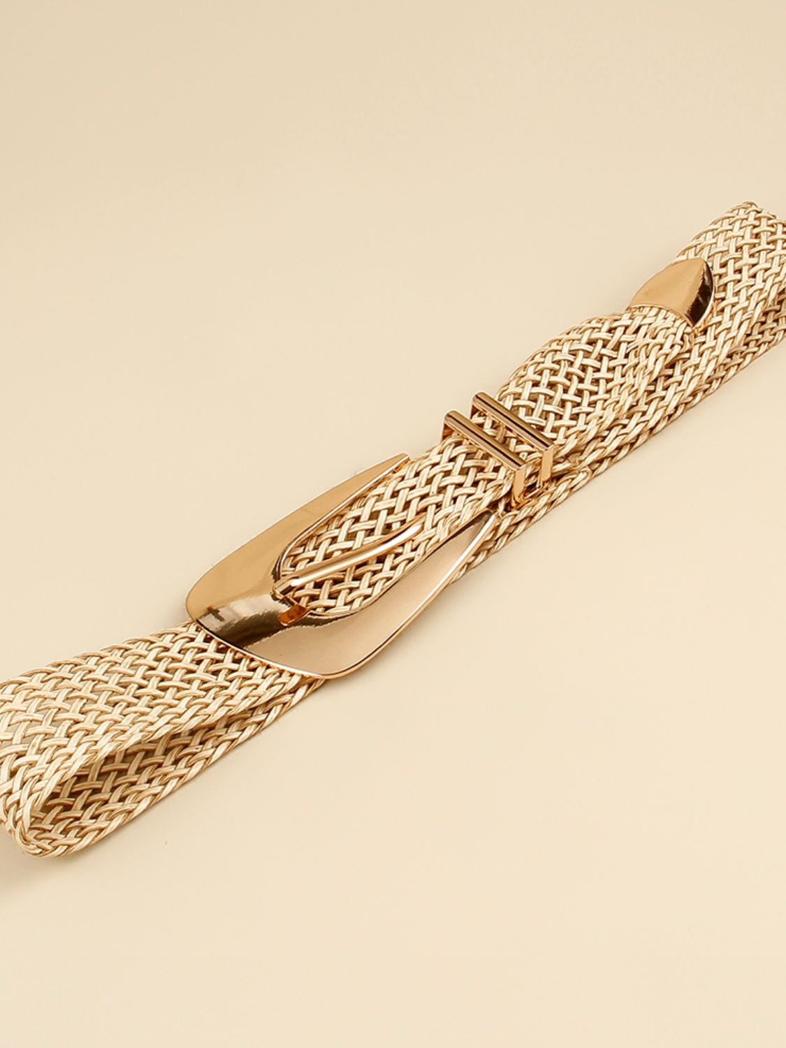 Gold-tone braided belt with irregular buckle, shown in profile close-up