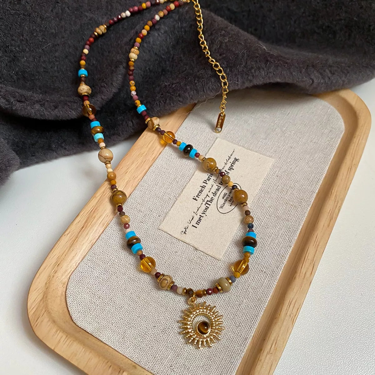 Multicolor beaded necklace with gold-tone sunflower pendant on display stand