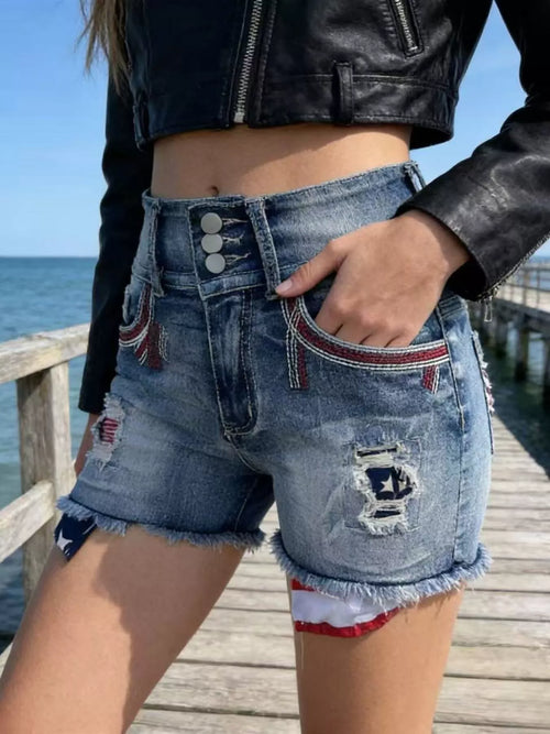 Blue distressed denim shorts with flag embroidery, frayed edges, front button