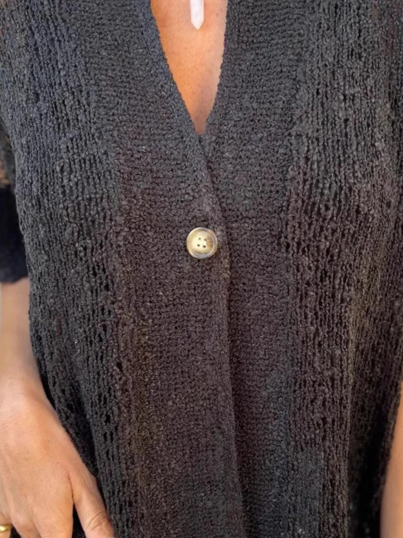 Textured openwork one-button cardigan front with V-neck and short sleeves in dark black.
