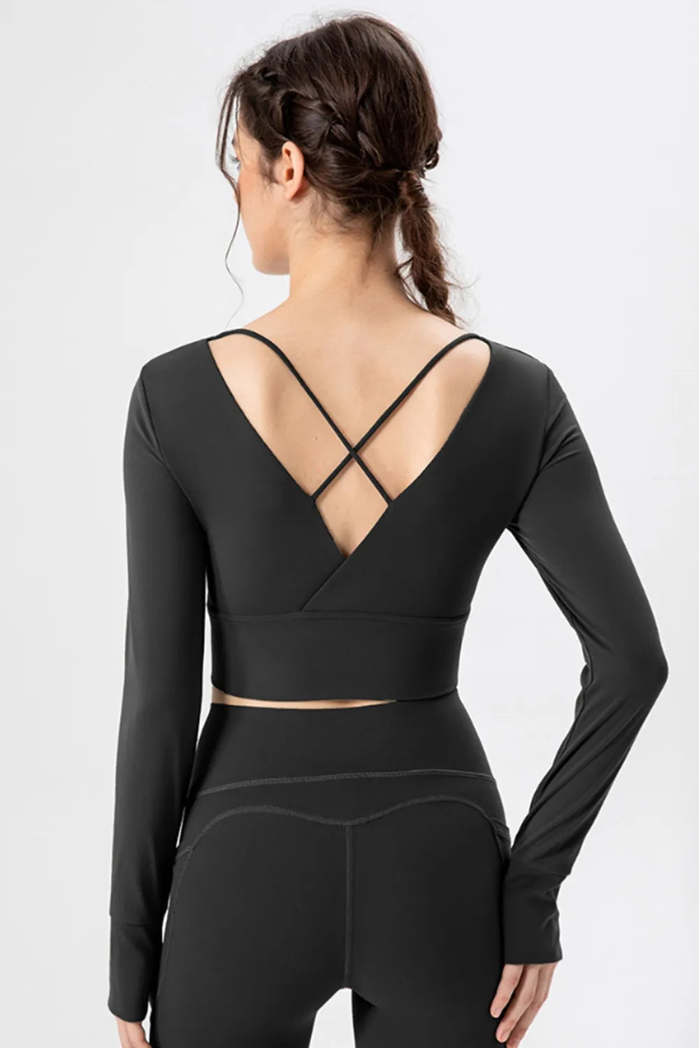 Back view of black long-sleeve active crop T-shirt with crisscross straps