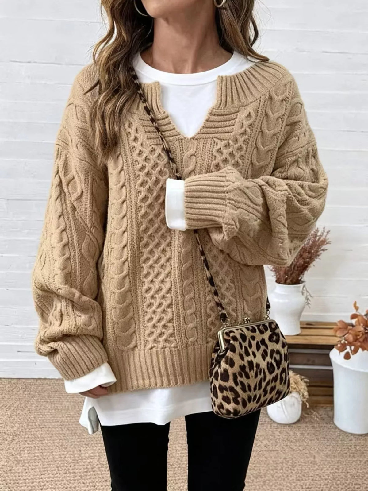 Tan cable knit sweater with dropped shoulders, V-neck, and ribbed cuffs