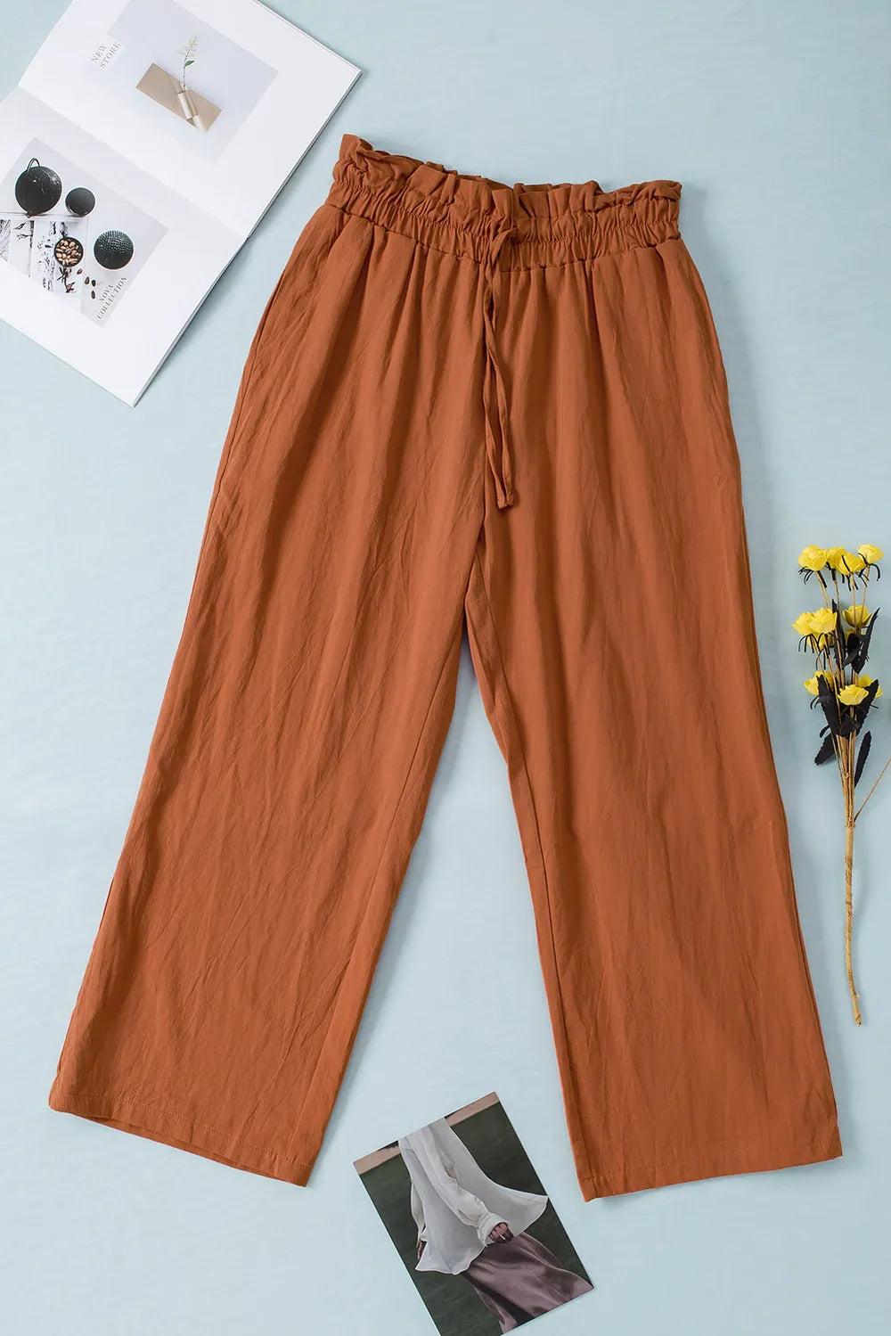 Terracotta drawstring paperbag waist wide-leg pants with elastic waistband and wide legs.