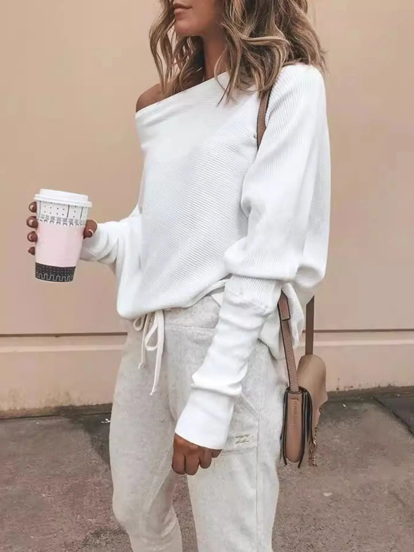 White one-shoulder ribbed knit sweater with off-shoulder neckline and long sleeves.