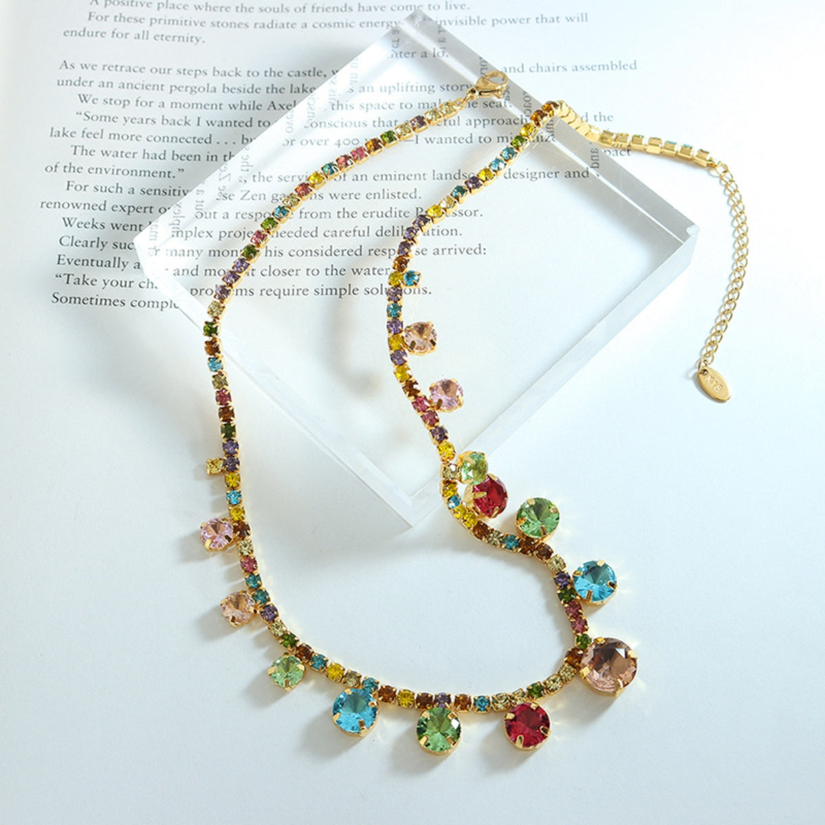 Crystal charm necklace laid flat, multicolor stones on gold-tone chain
