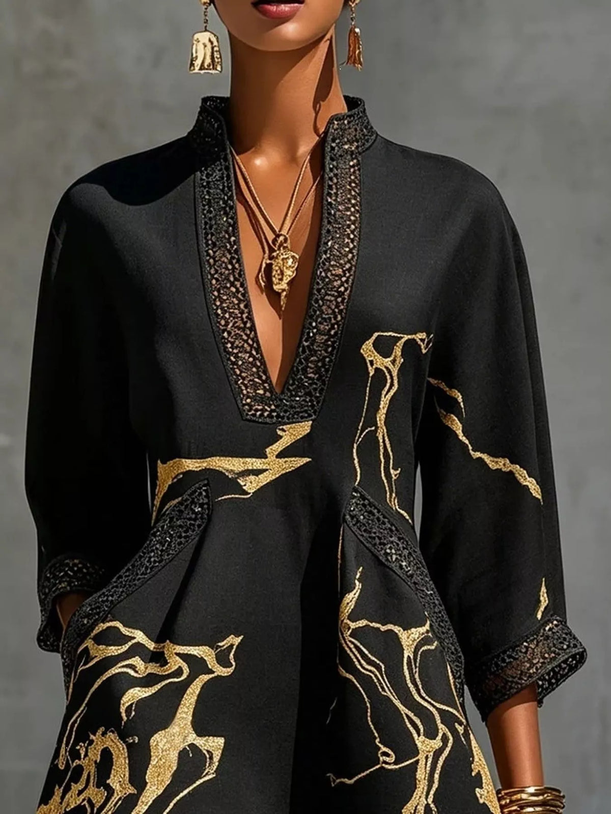 Black mini dress with V-neck lace trim, three-quarter sleeves, and gold abstract print
