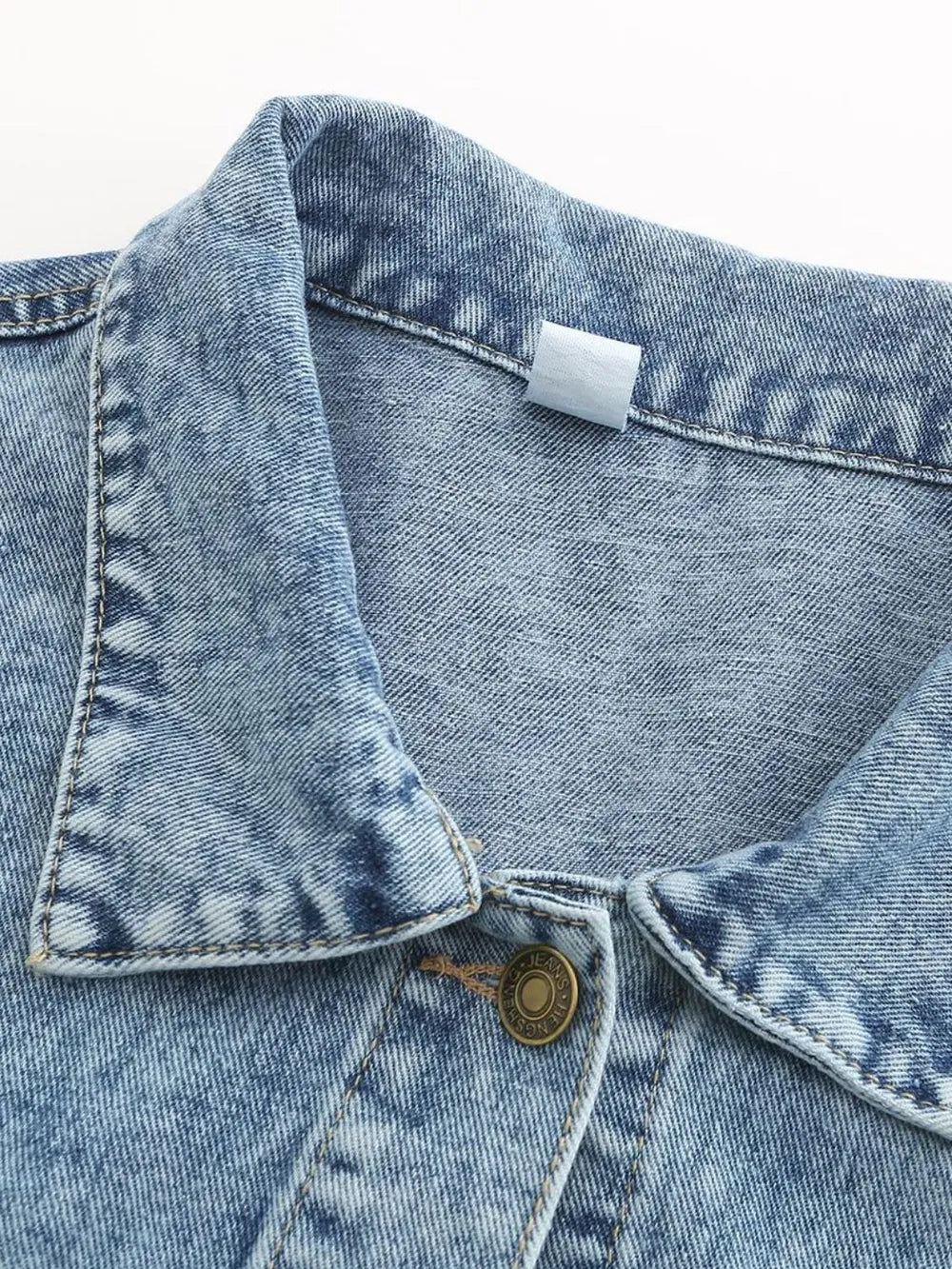 Light wash denim jacket close-up: button placket and pointed collar