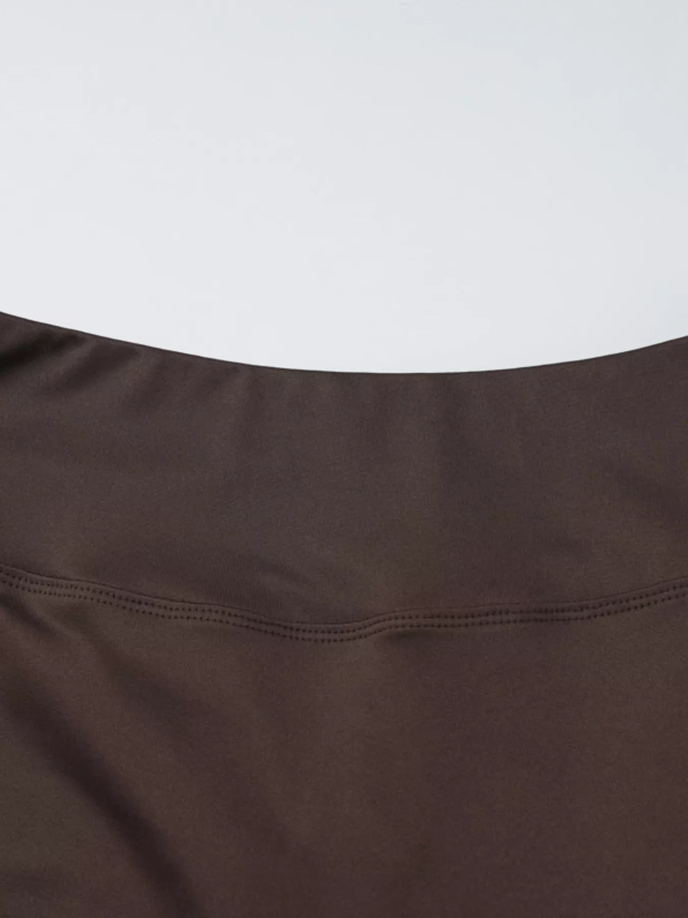 Dark brown fabric close-up of halter crop top hem seam and stitching