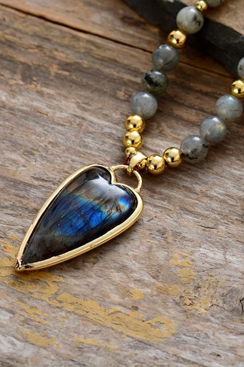 Beaded necklace detail: teardrop blue pendant with blue-gray beads and gold beads