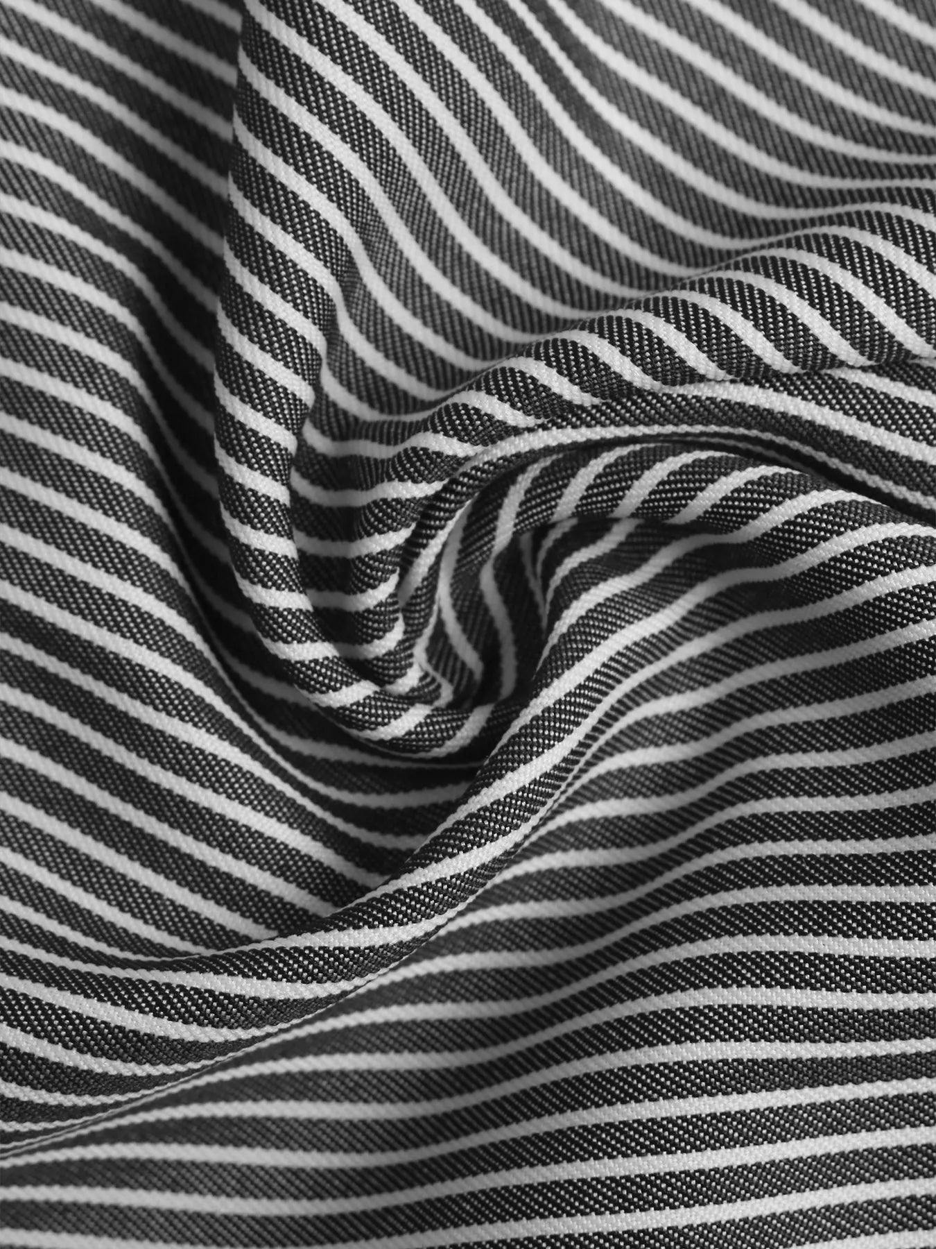 Close-up of striped pants fabric with gathered folds, black and white vertical stripes