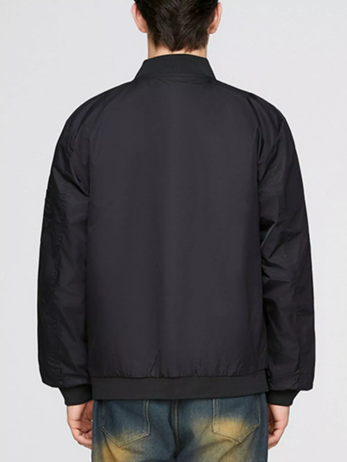 Back view of black bomber jacket with ribbed hem and full-length sleeves