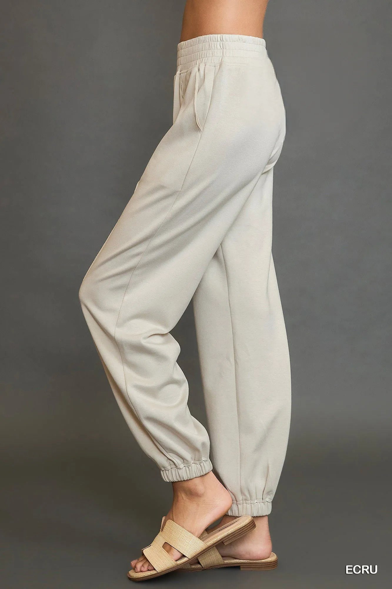 Ecru drawstring jogger pants, angled side view with gathered elastic ankle cuffs