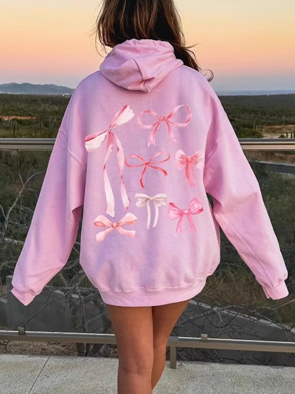 Pastel purple long-sleeve hoodie with large pink bow graphic on the back