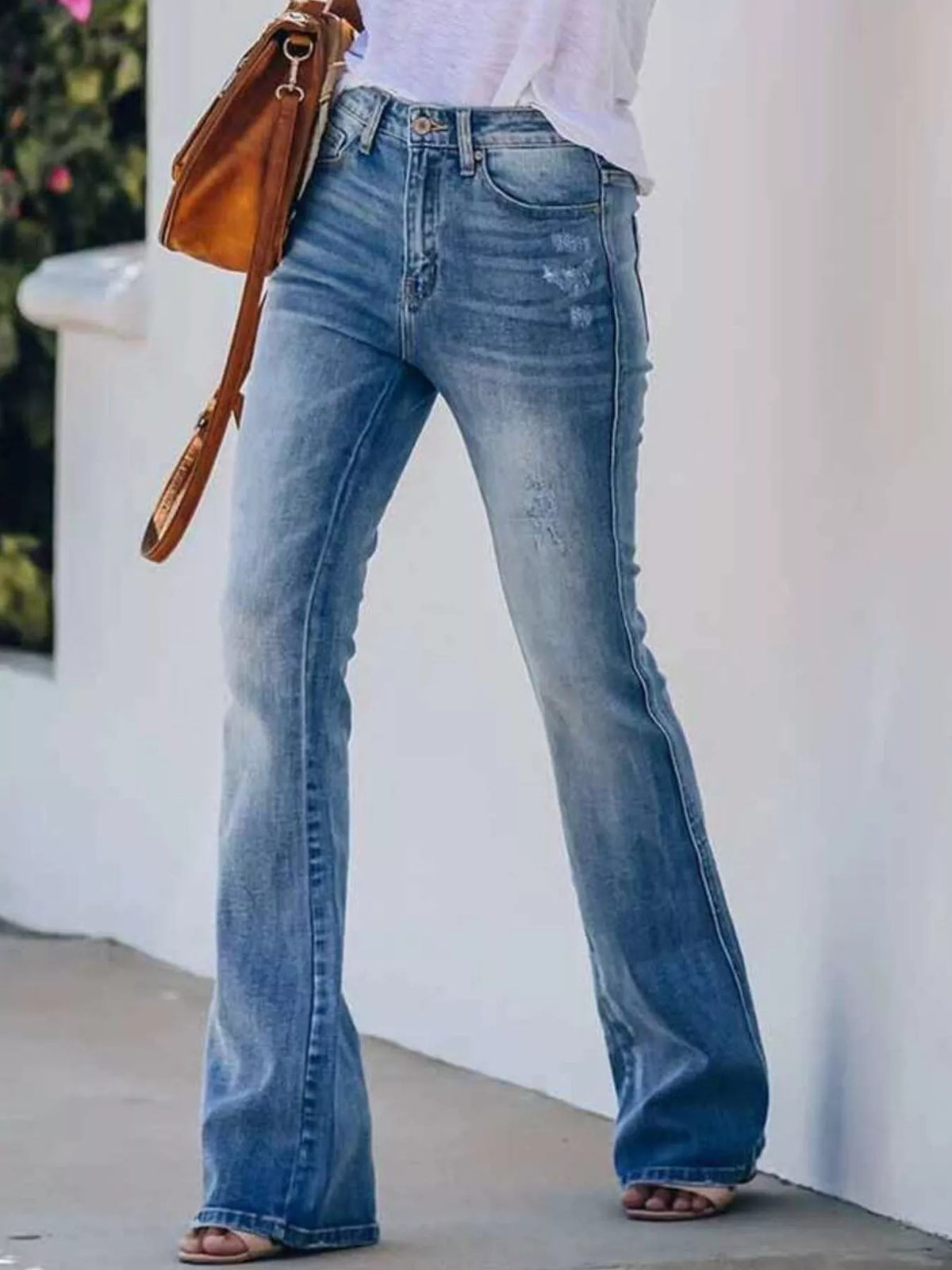 Blue high-rise distressed flare jeans with whiskering, small rips, and wide bell hems