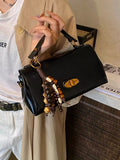 Flap PU shoulder bag in black with gold hardware and beaded tassel charm