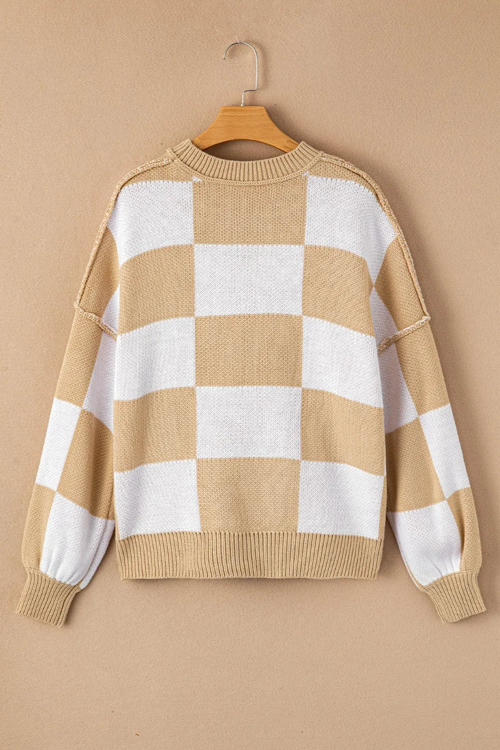 Tan and white checkered sweater on hanger with long sleeves and ribbed crew neckline