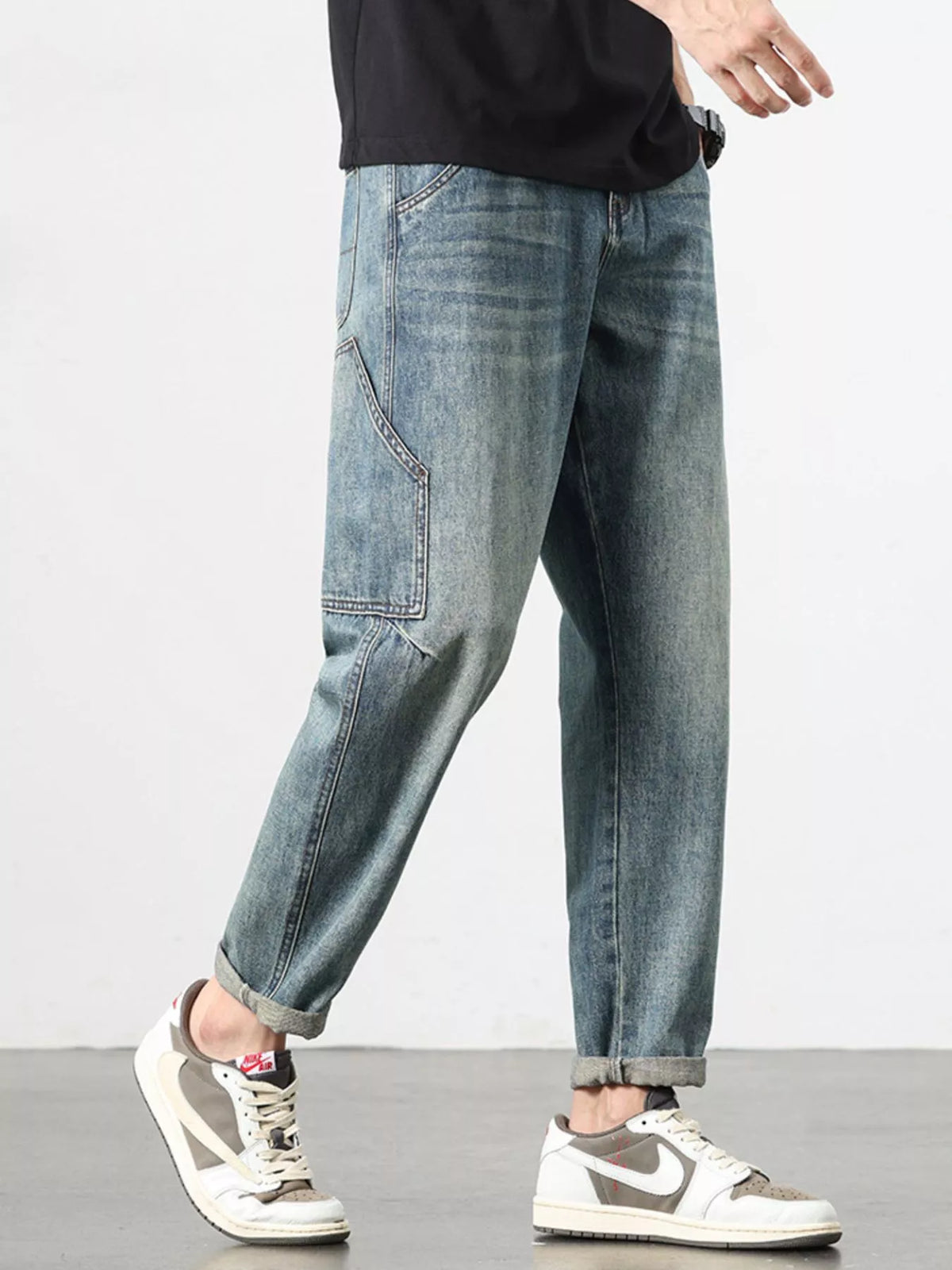 Relaxed washed blue jeans, visible side seams and angled pocket stitching.
