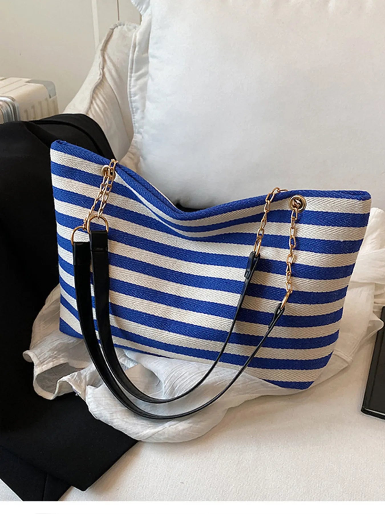 Blue and white striped shoulder bag with gold chain handles and black bottom panel.